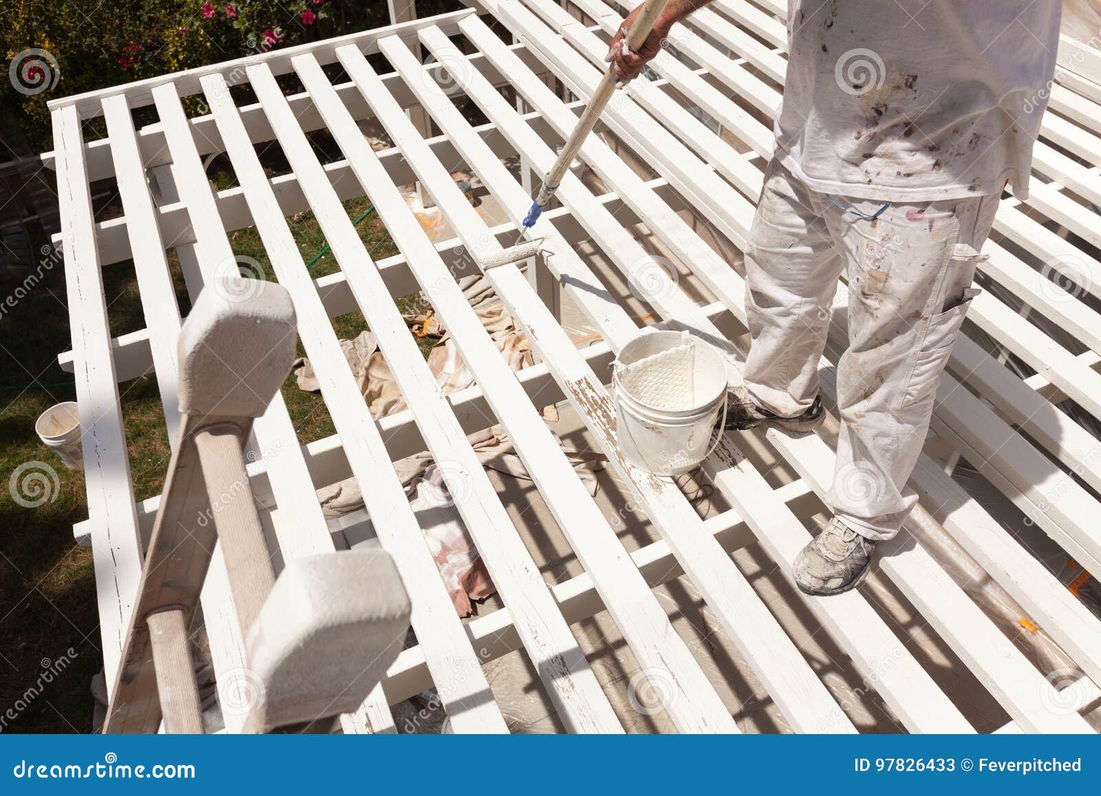 professional painter rolling white paint onto the top of a home