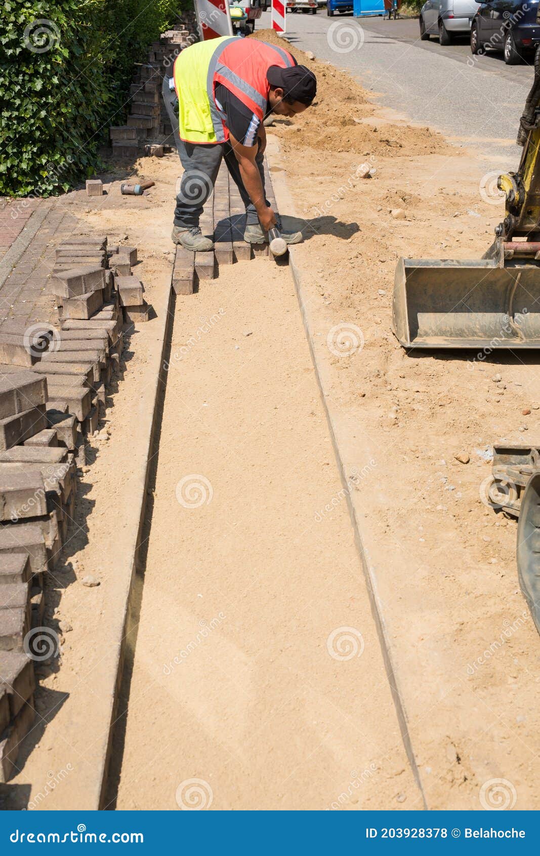 professional paver worker placing pave stones and using a hammer.