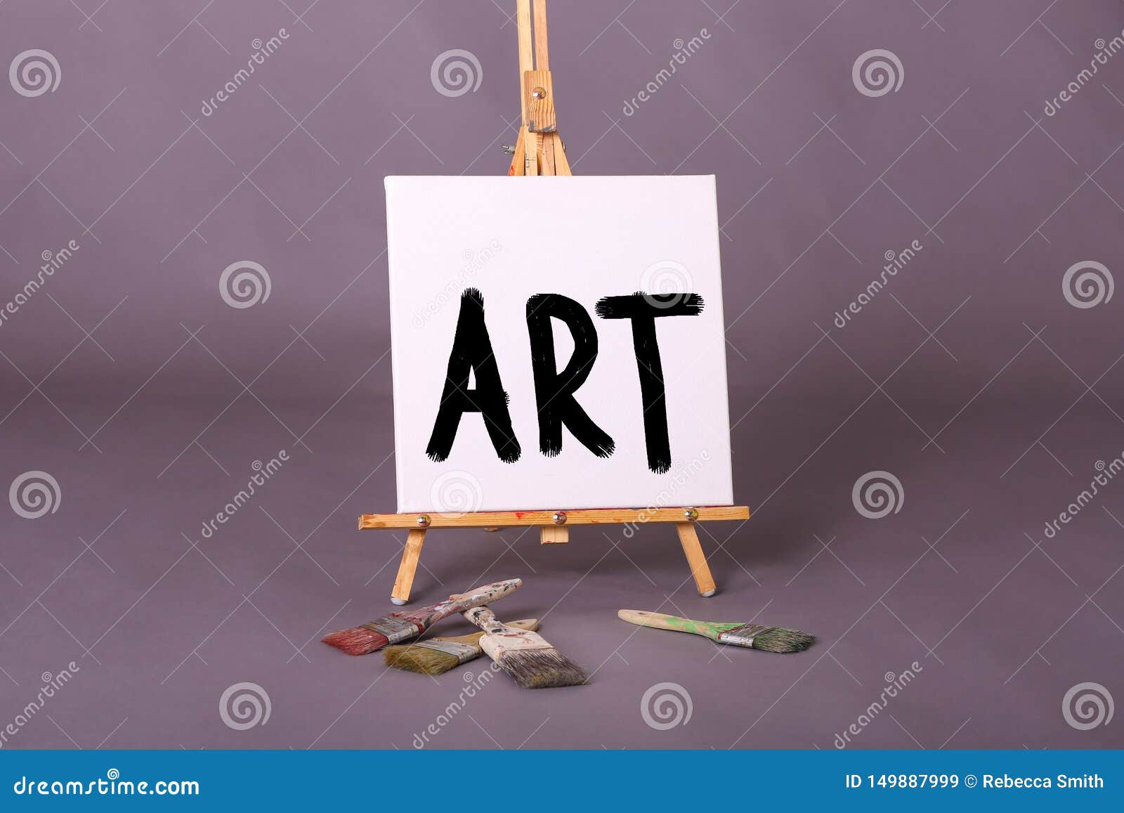 The Word ART Painted in Black Paint on White Canvas on Easel Paint Brushes Scattered Stock Image