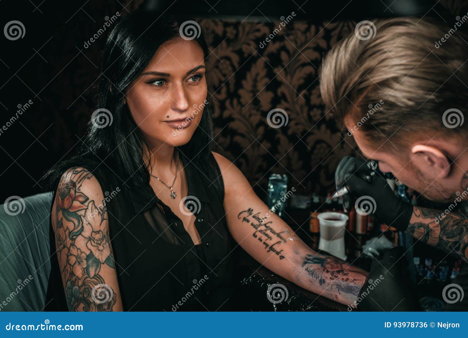 professional tattoo artist makes a tattoo on a young girl`s hand