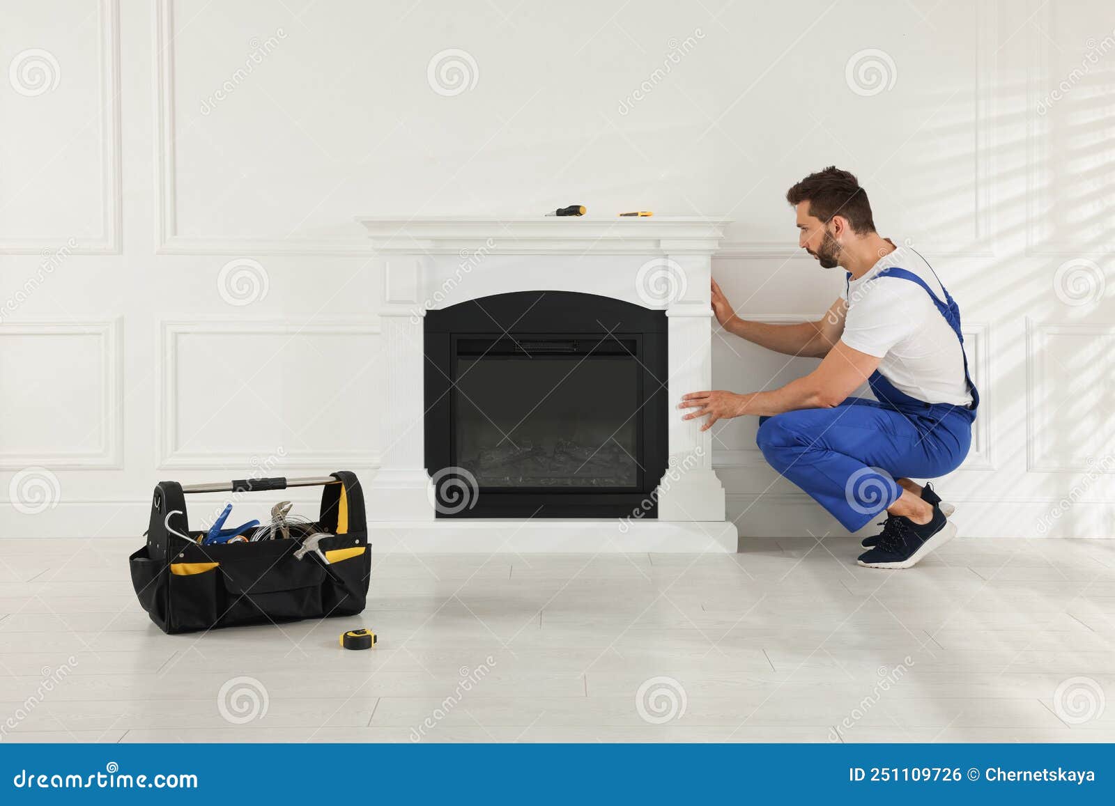 Professional Technician Installing Electric Fireplace in Room Stock