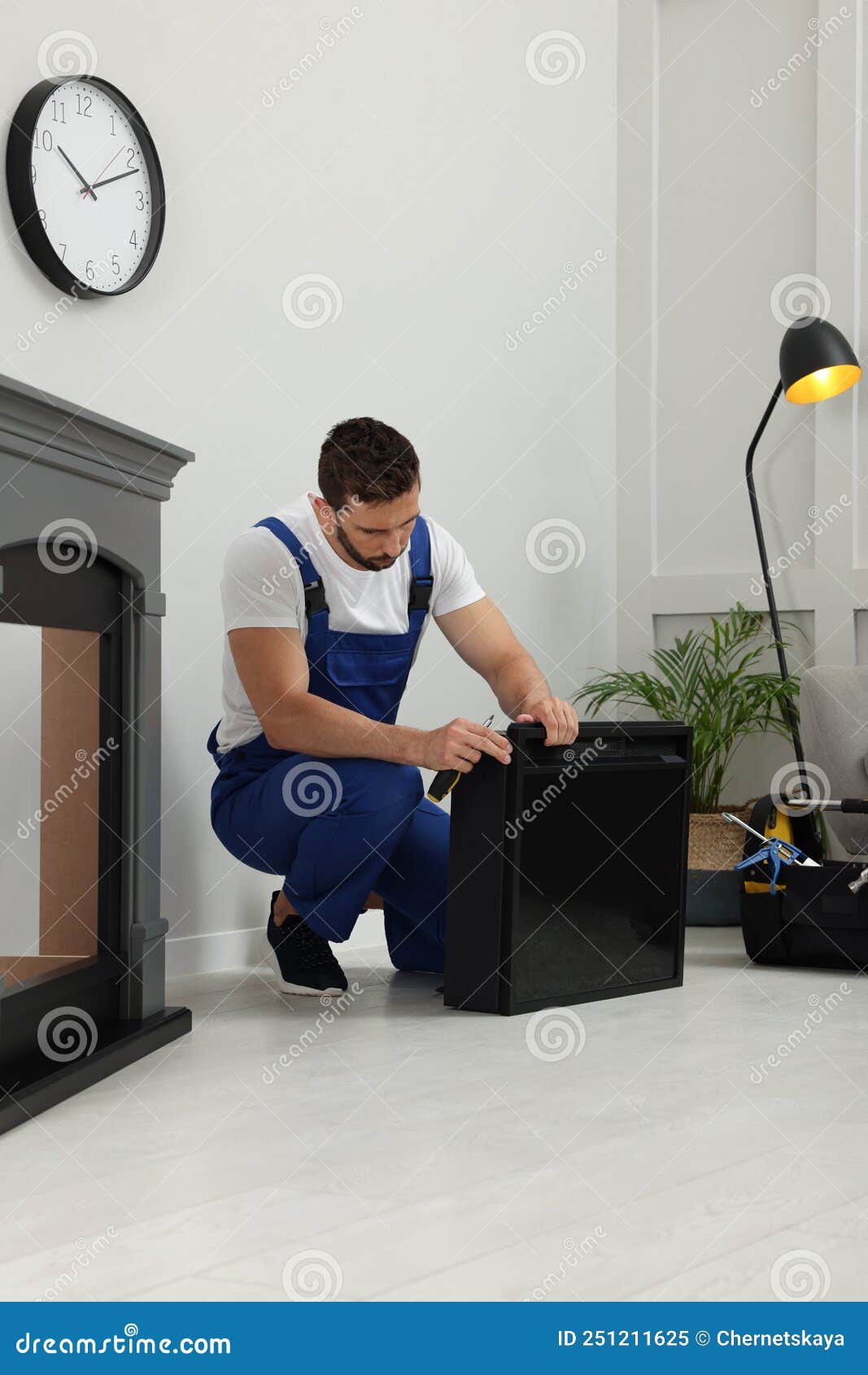 Professional Technician with Screwdriver Installing Electric Fireplace