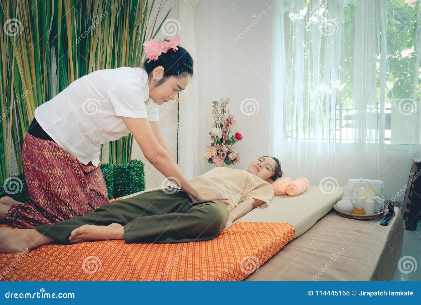 Professional Therapist Giving Traditional Thai Massage To A Woman In
