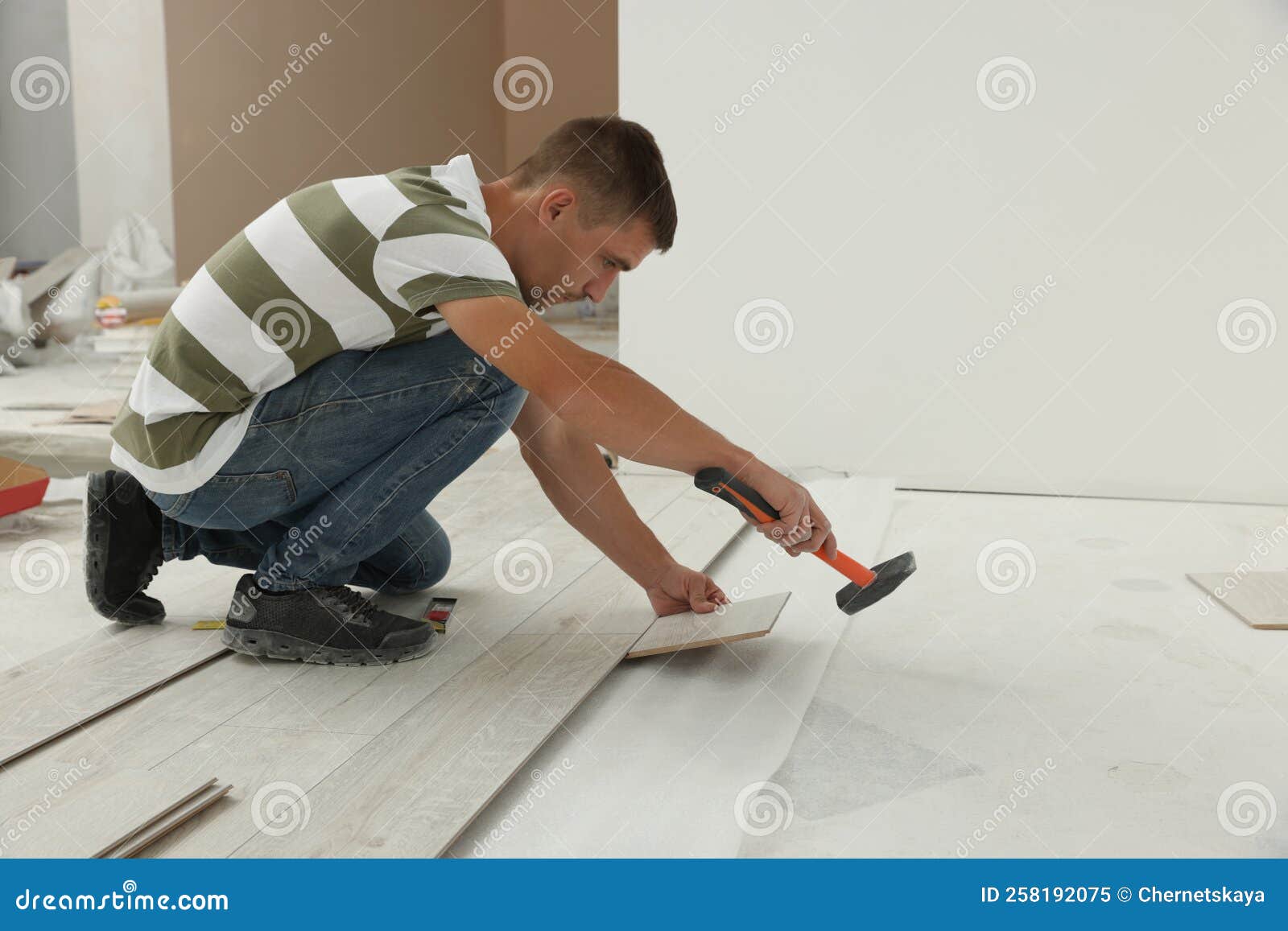 Professional Worker Using Hammer during Installation of New Laminate