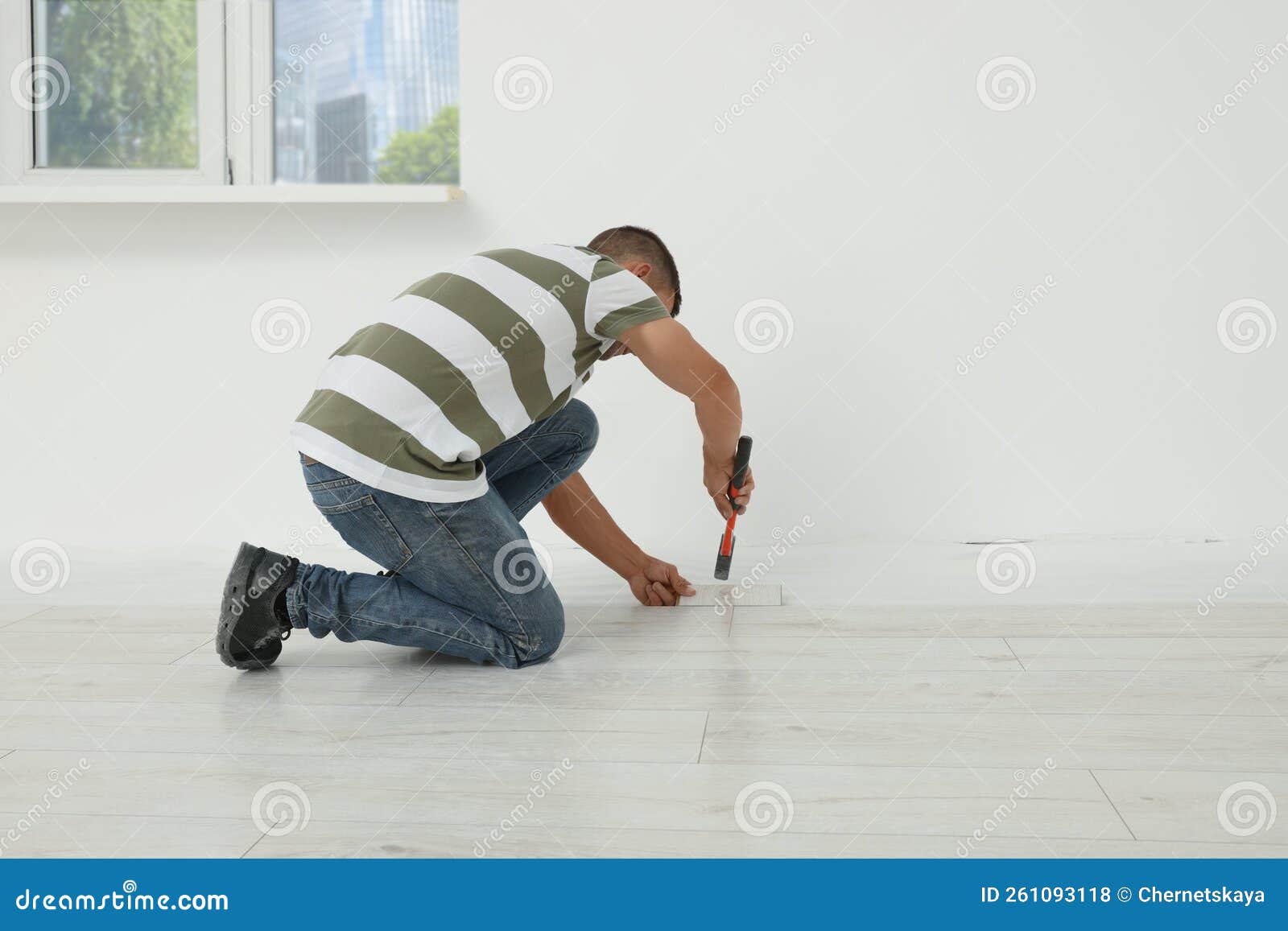 Professional Worker Using Hammer during Installation of New Laminate