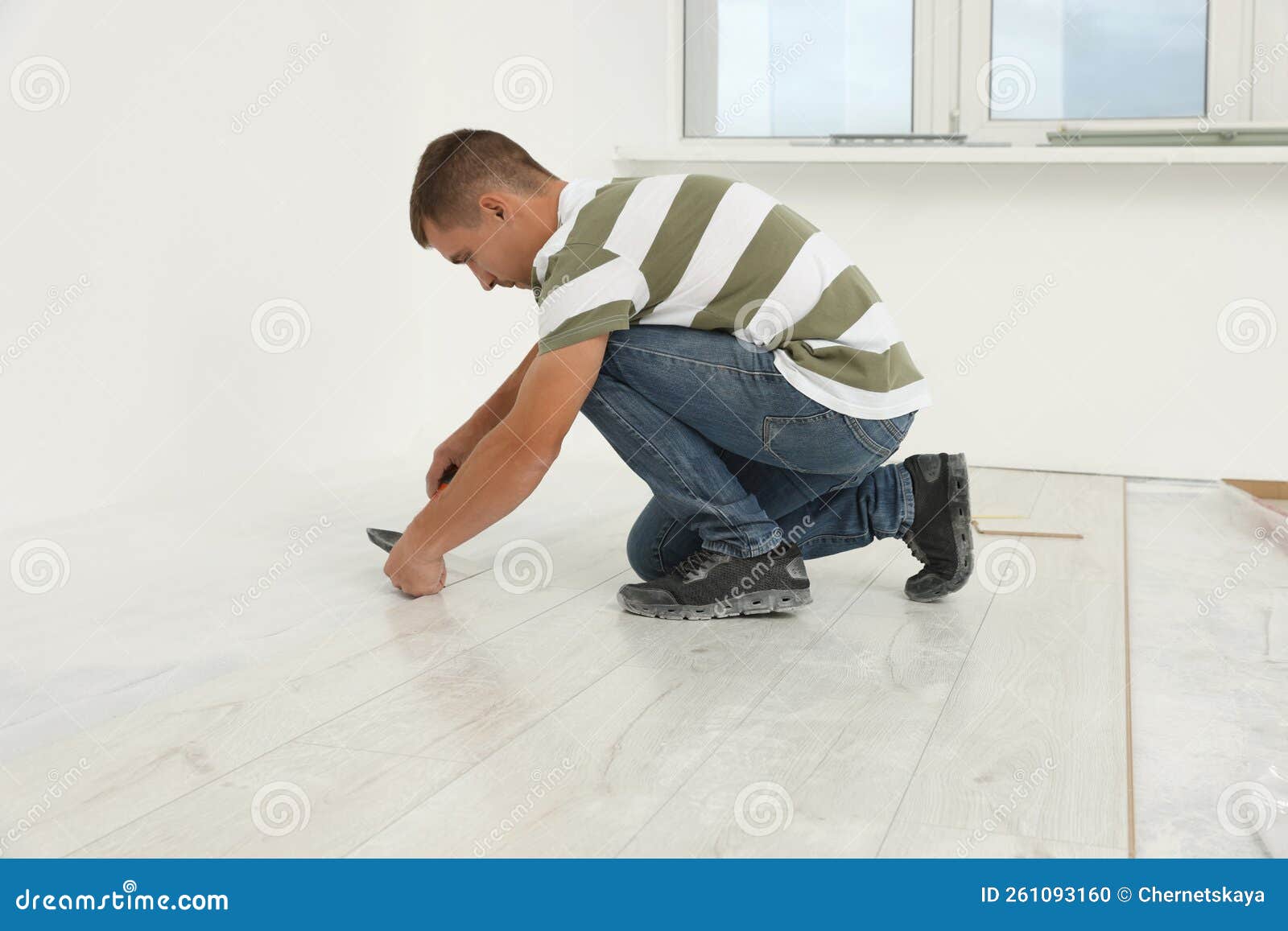 Professional Worker Using Hammer during Installation of New Laminate