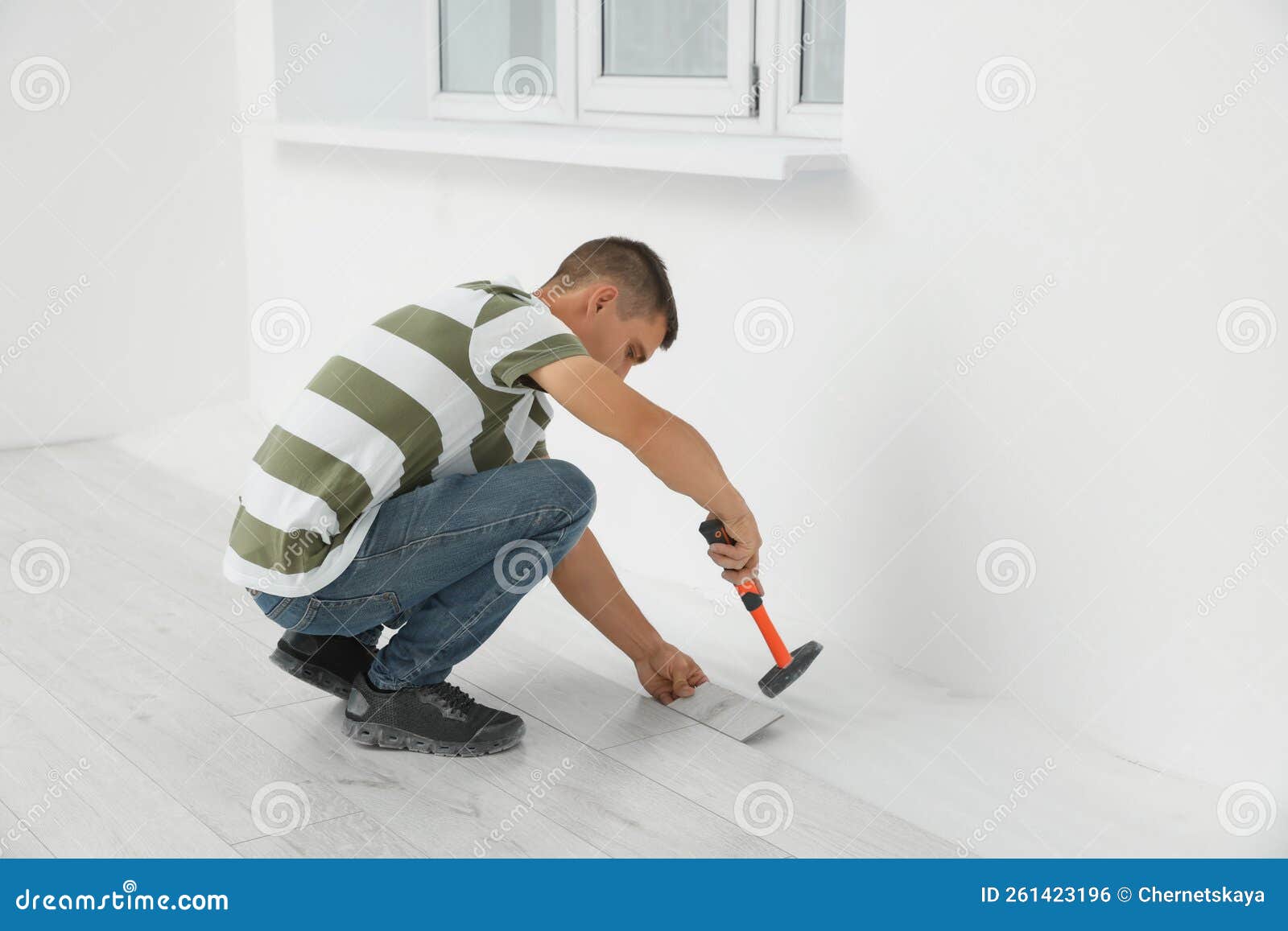 Professional Worker Using Hammer during Installation of New Laminate