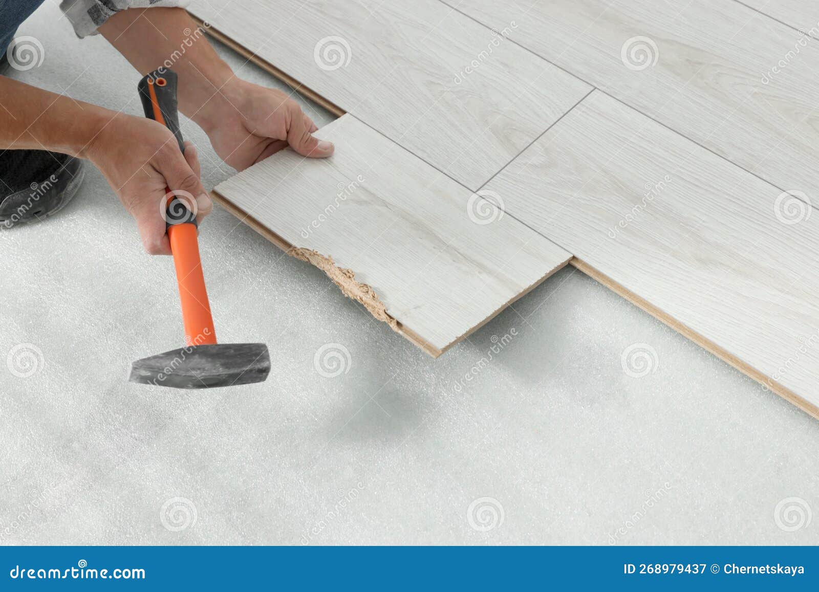 Professional Worker Using Hammer during Installation of New Laminate