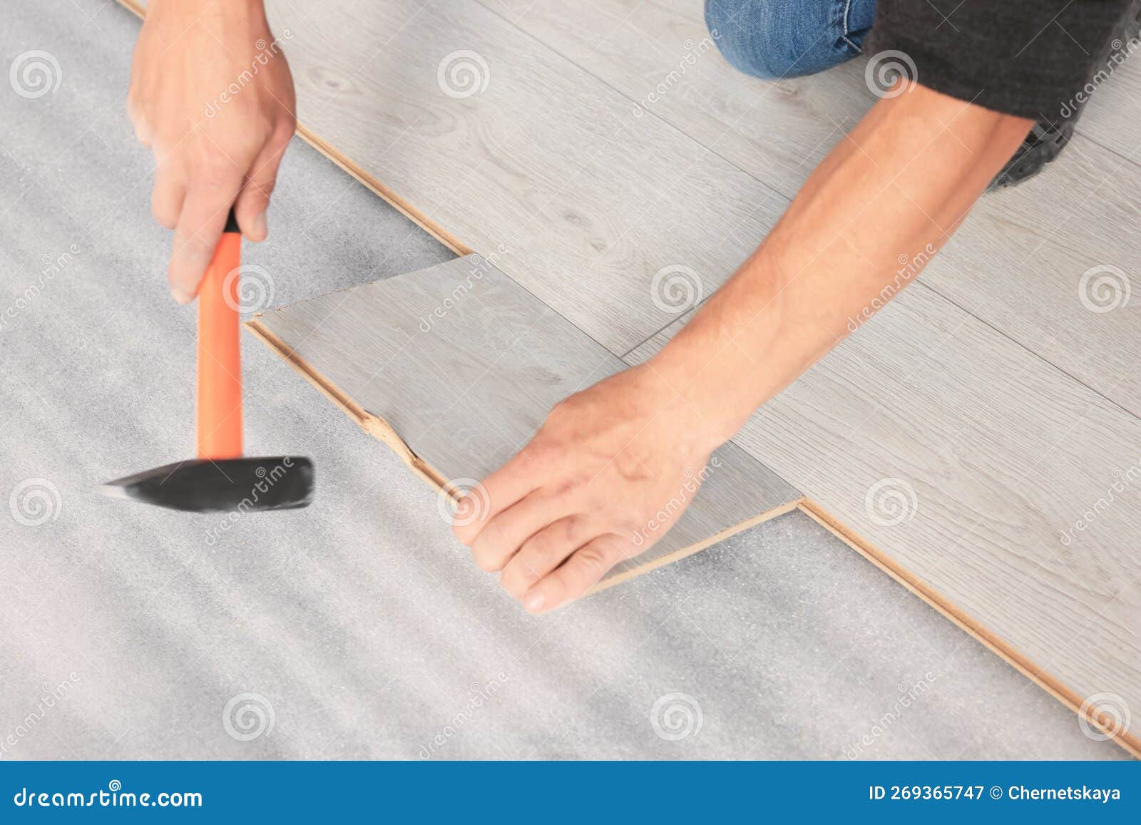 Professional Worker Using Hammer during Installation of New Laminate
