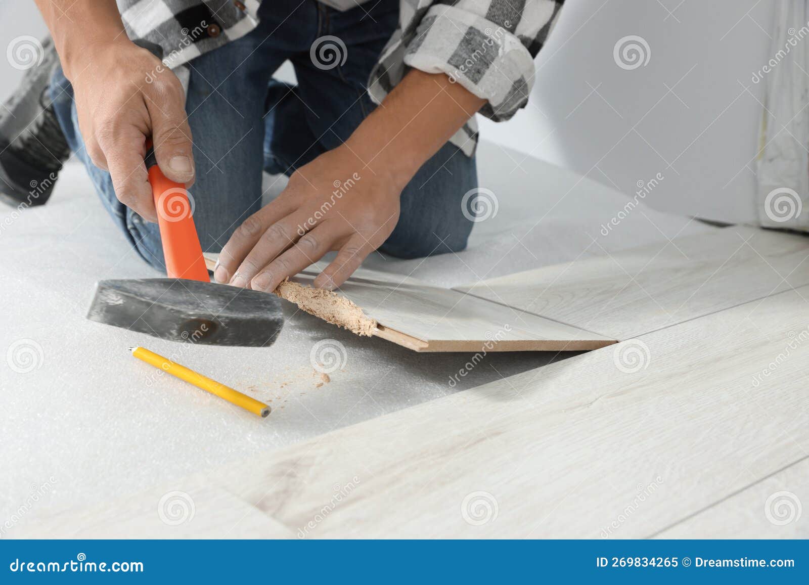 Professional Worker Using Hammer during Installation of New Laminate