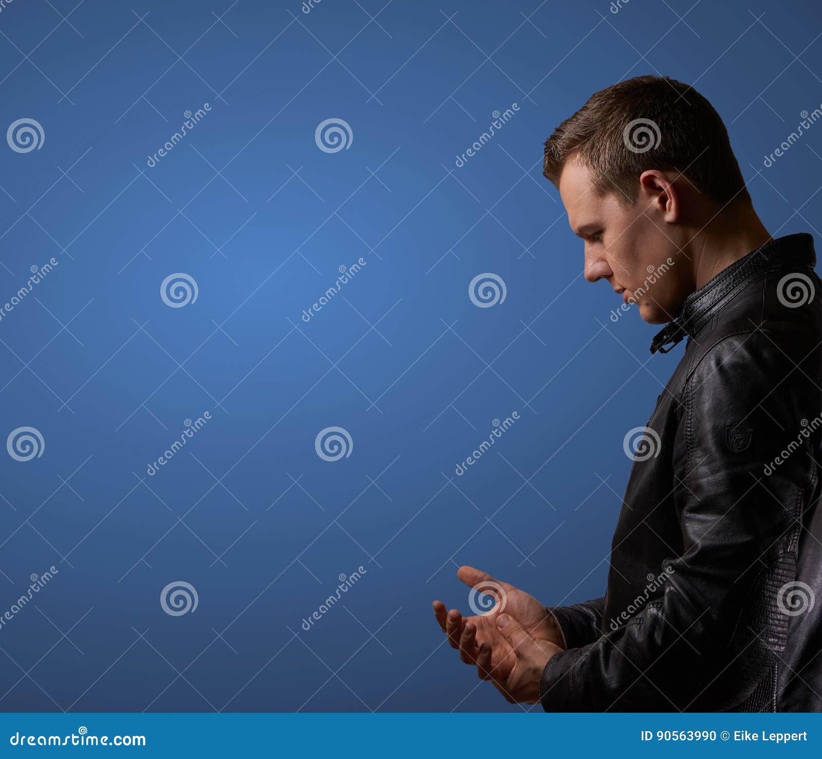 profil shot from a young man in leatherjacket, rubbing his hand with copyspace