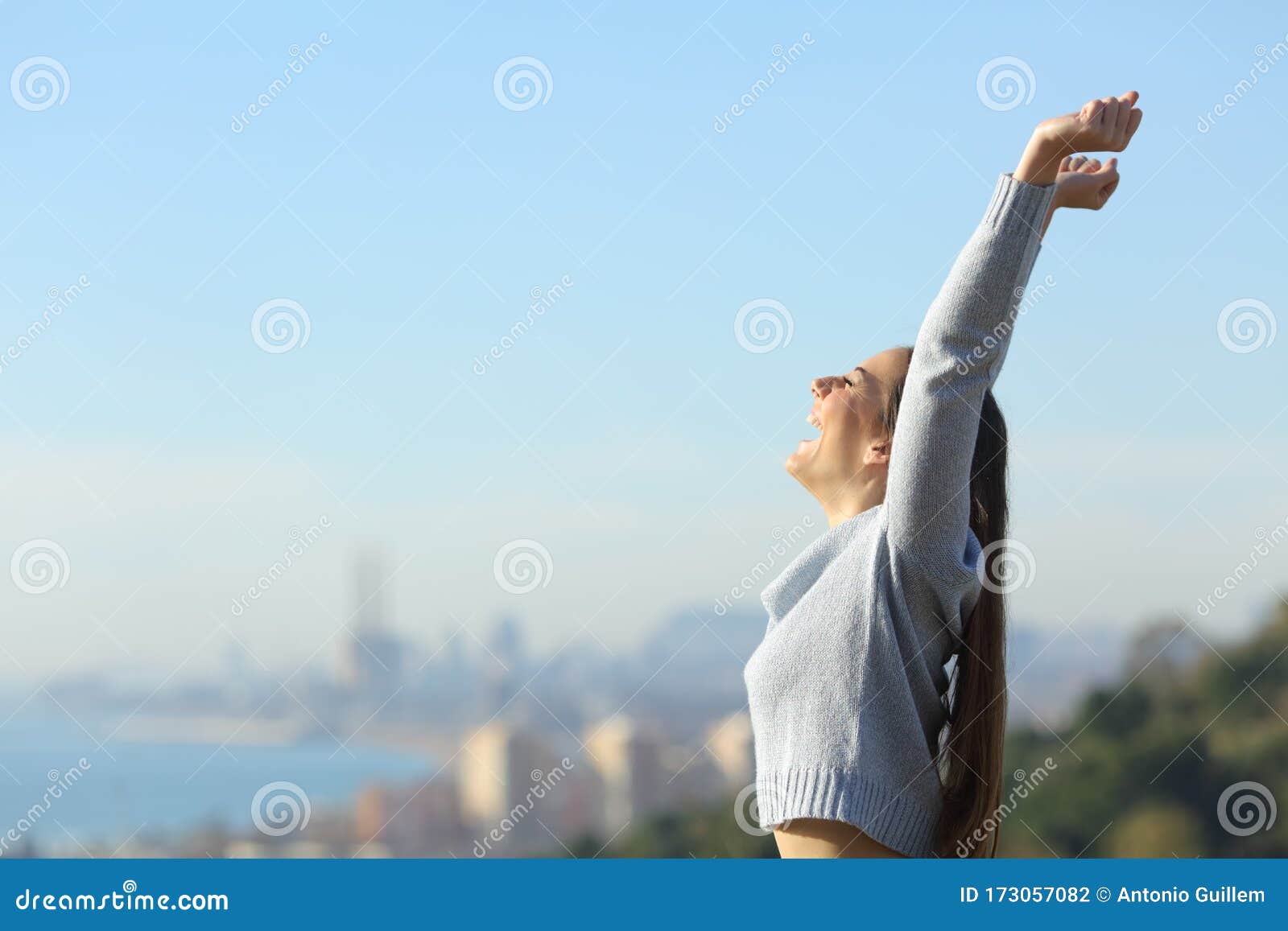 profile of excited woman raising arms in city outskirts