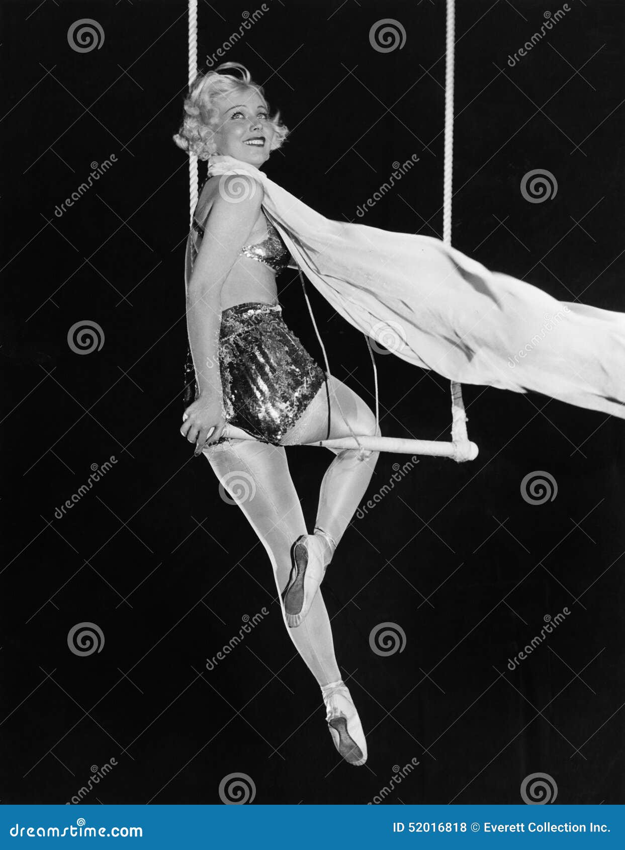 profile of a female circus performer performing on a trapeze bar