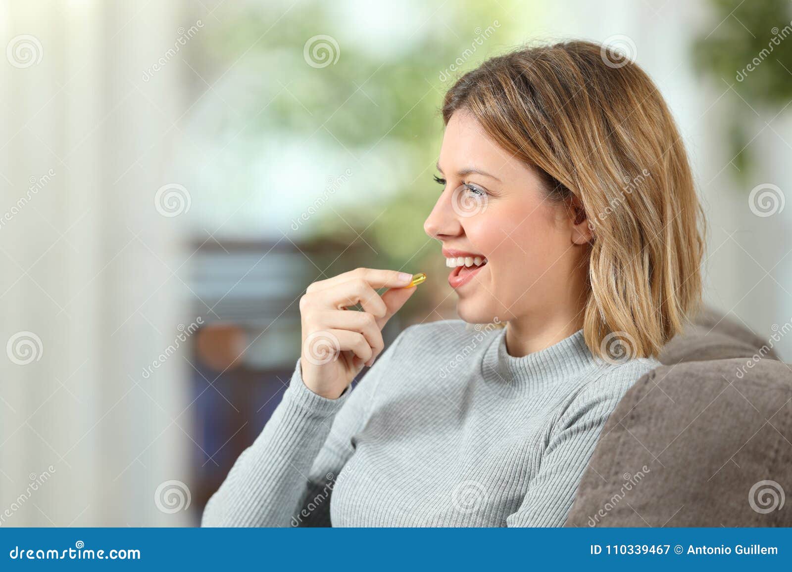 profile of a happy woman taking a vitamin pill
