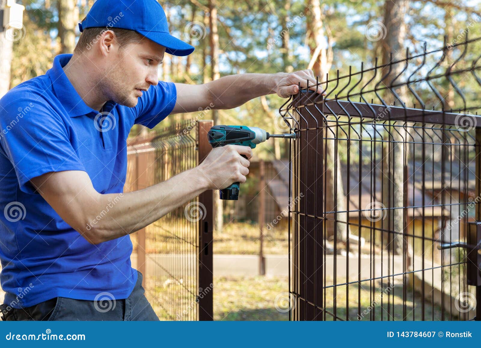 property territory fencing - man screws metal fence panel