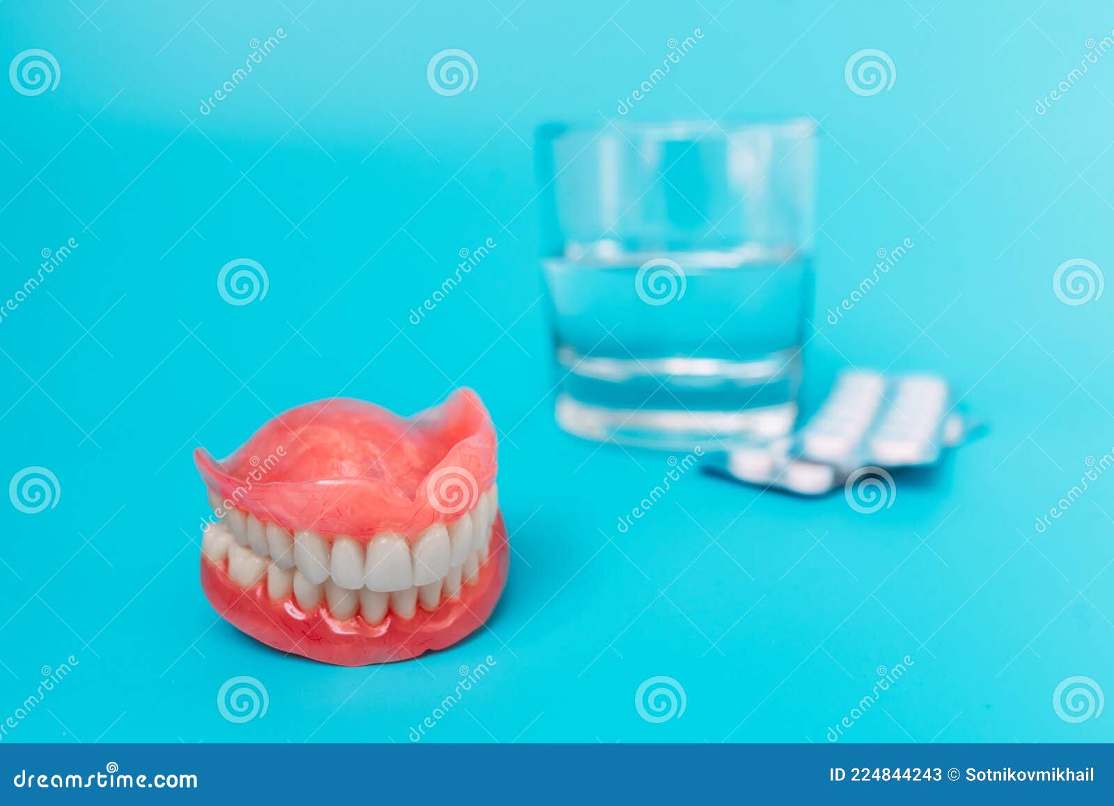 A Prosthesis and a Glass with a Solution. Dental Prosthesis Care. Full Removable Plastic Denture