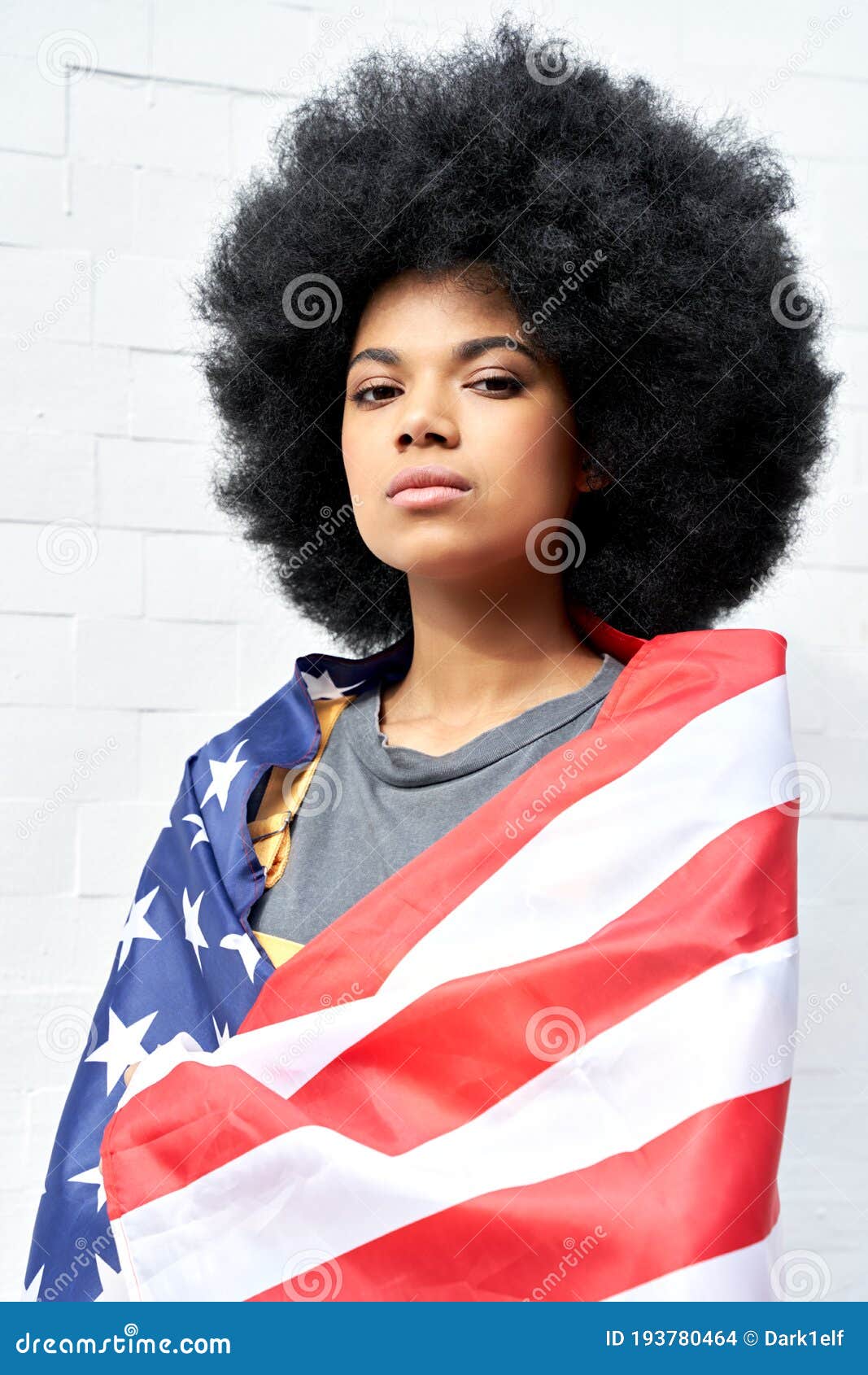 proud african woman stand on white background wrapped in usa flag, portrait.