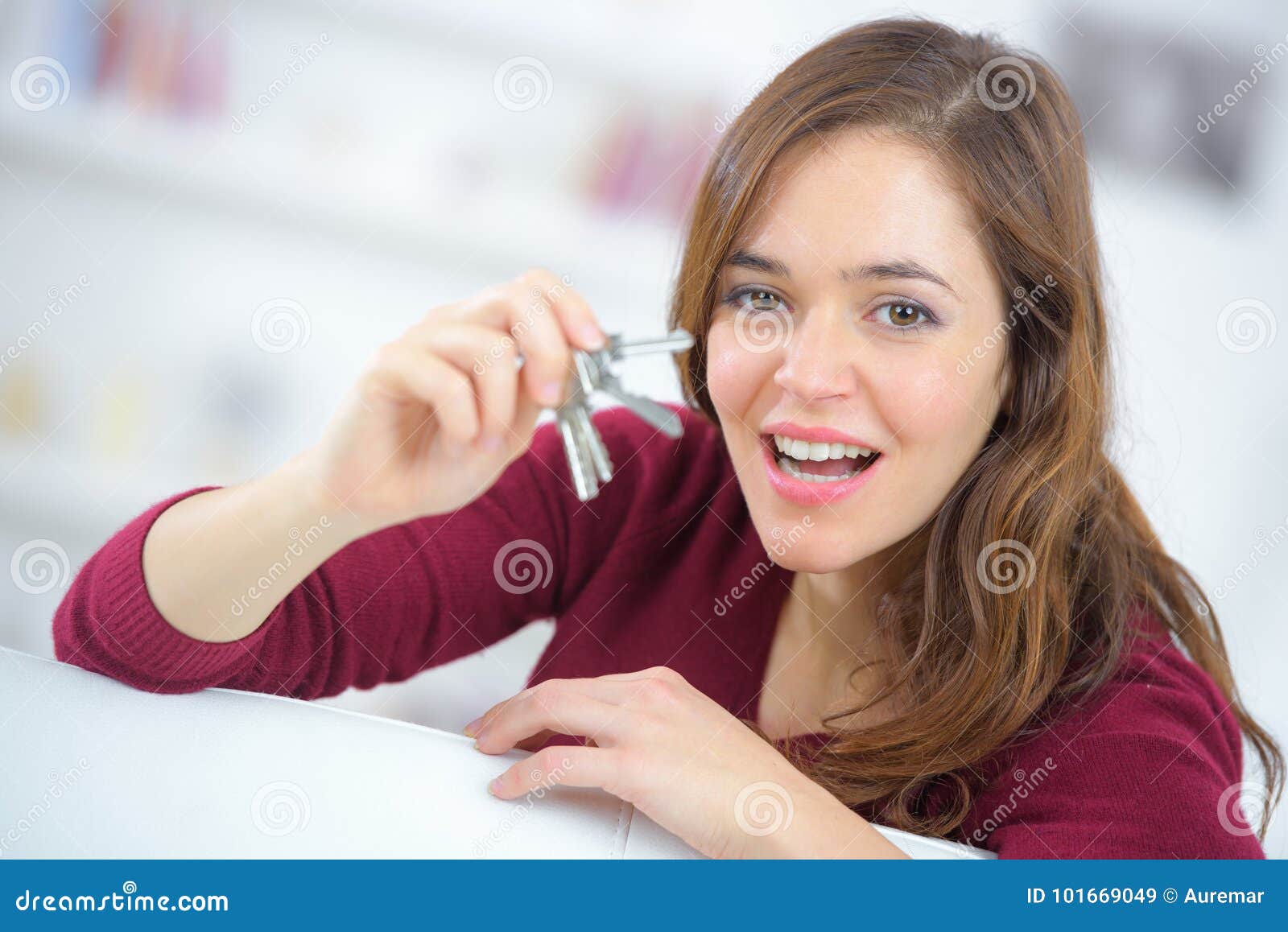 proud young woman holding up set house keys