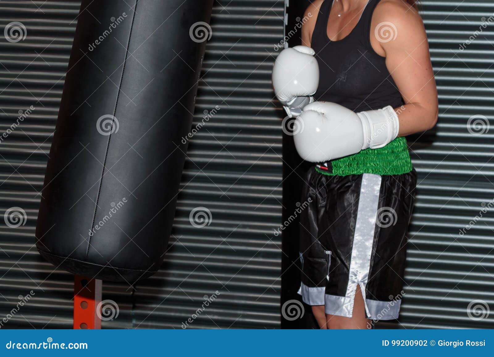 Pugilist Girl at Boxing Training with Black Punching Bag Stock Photo