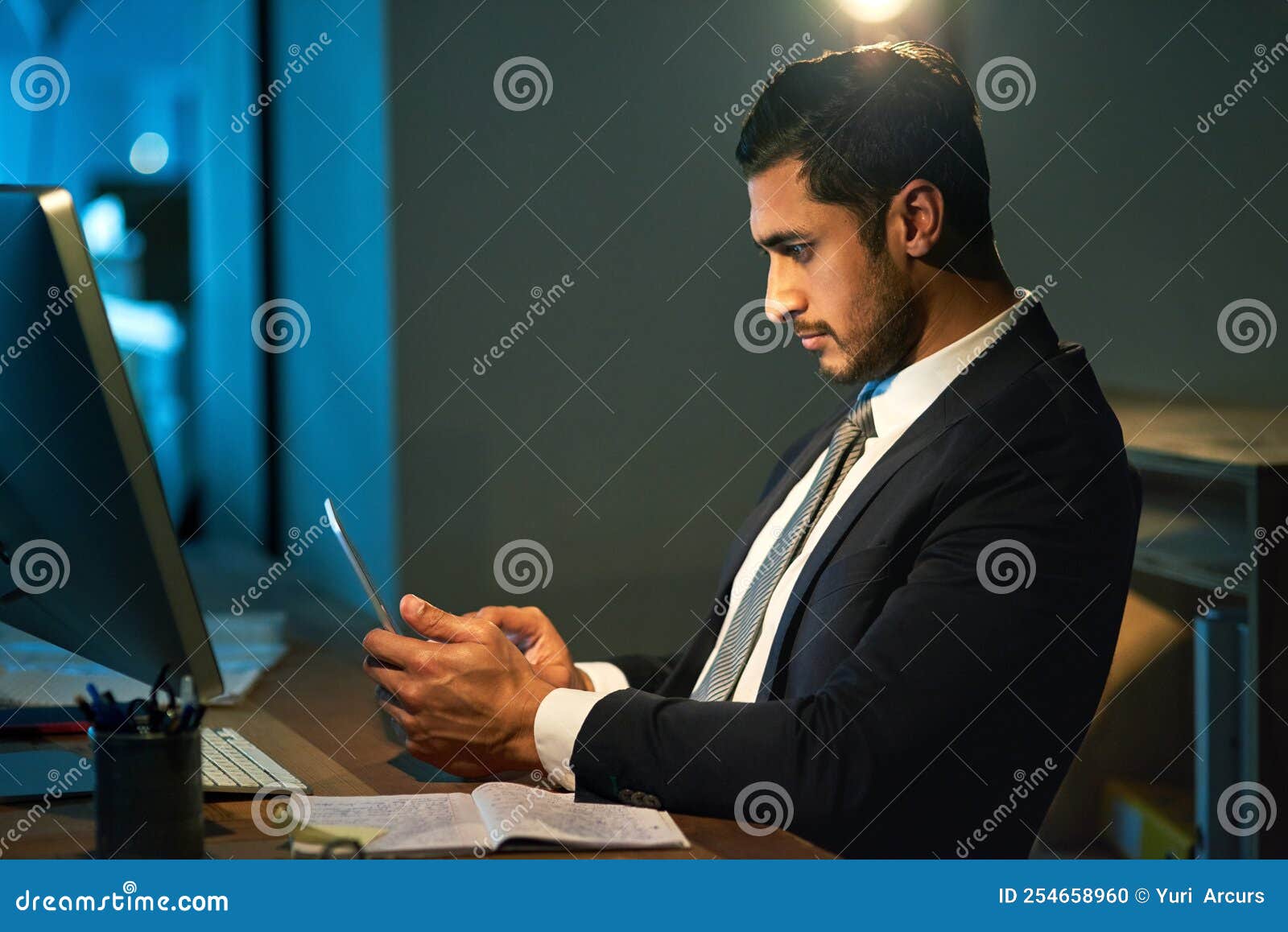 pulling an all nighter. a young businessman using a digital tablet during a late night at work.