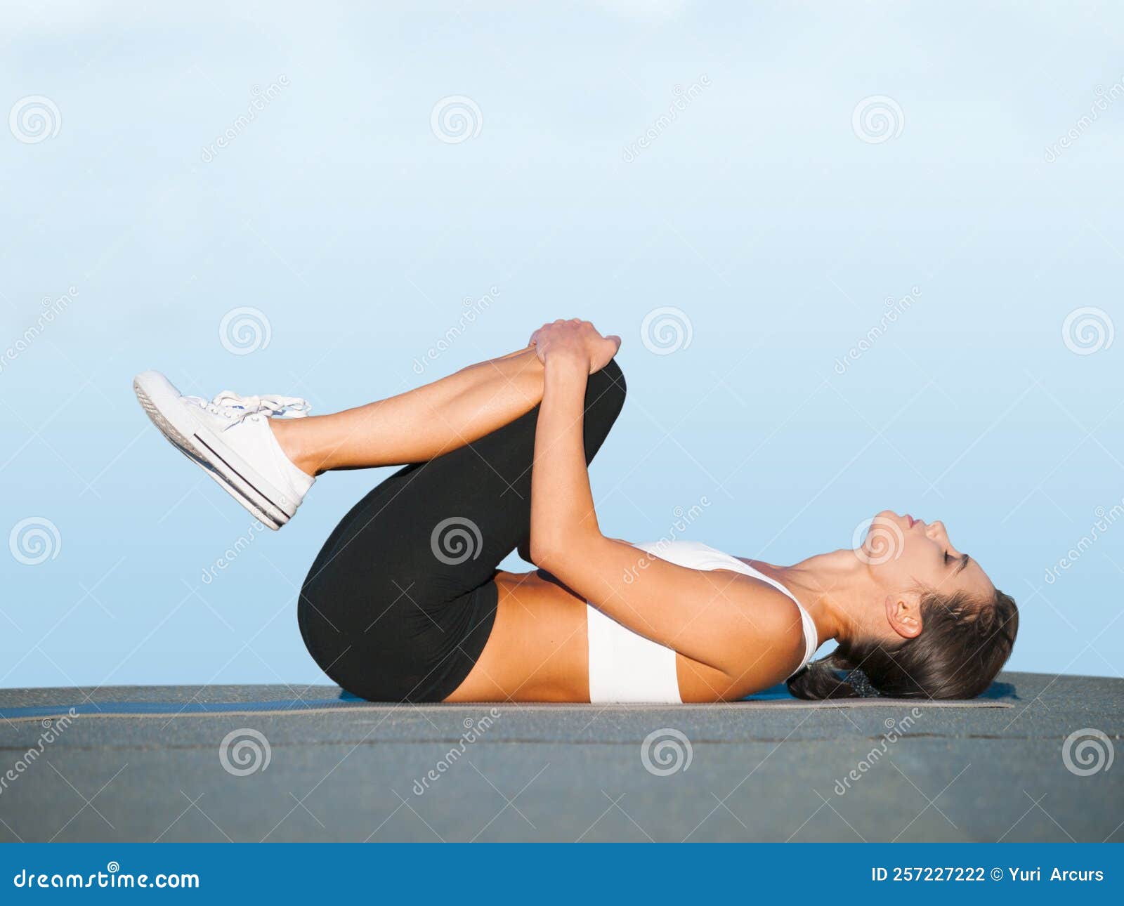 Pulling Her Knees in for a Deep Stretch. a Young Woman Doing Yoga Stretches Outdoors. Stock