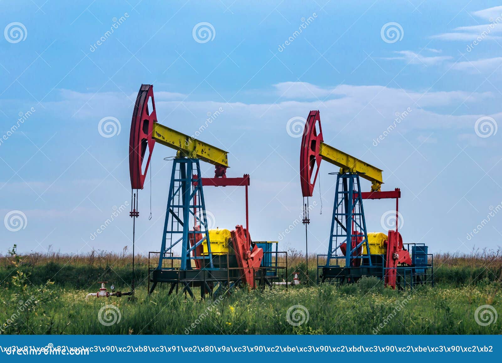 Pumpjacks Operating at an Oil Well in Field Under Cloudy Sky Stock