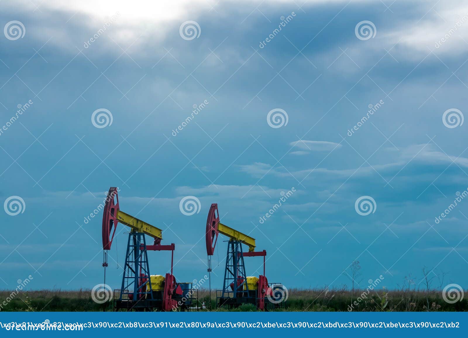 Pumpjacks Operating at an Oil Well in Field Under Cloudy Sky Stock