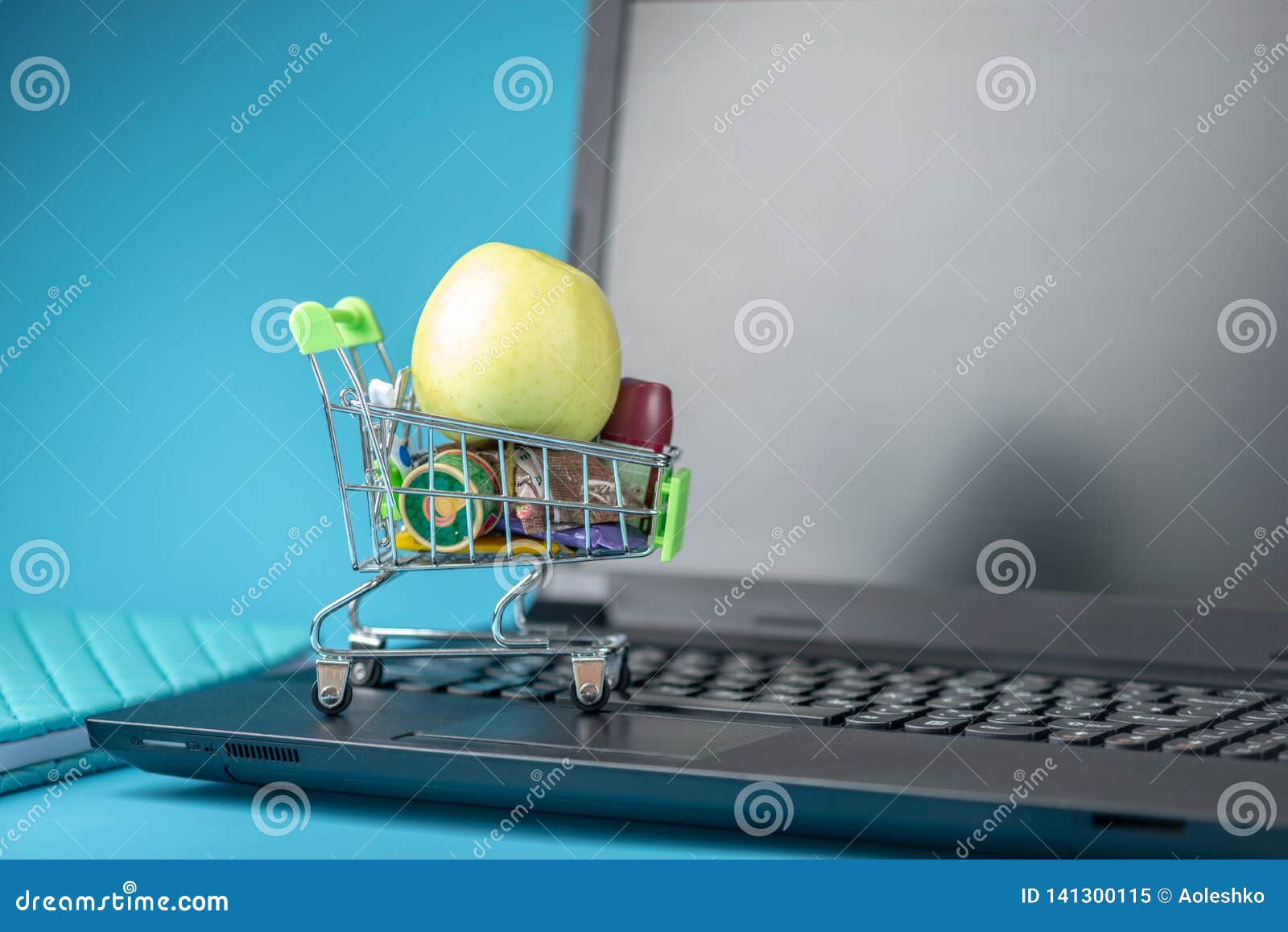 daily purchases in the shopping cart on the laptop keyboard on a blue background. concept of shopping in online stores