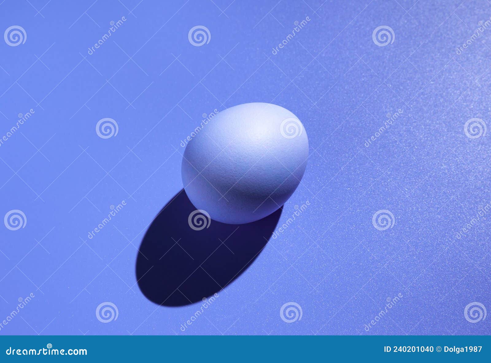 A Purple Egg with a Hard Shadow on a Purple Background. Stock Photo