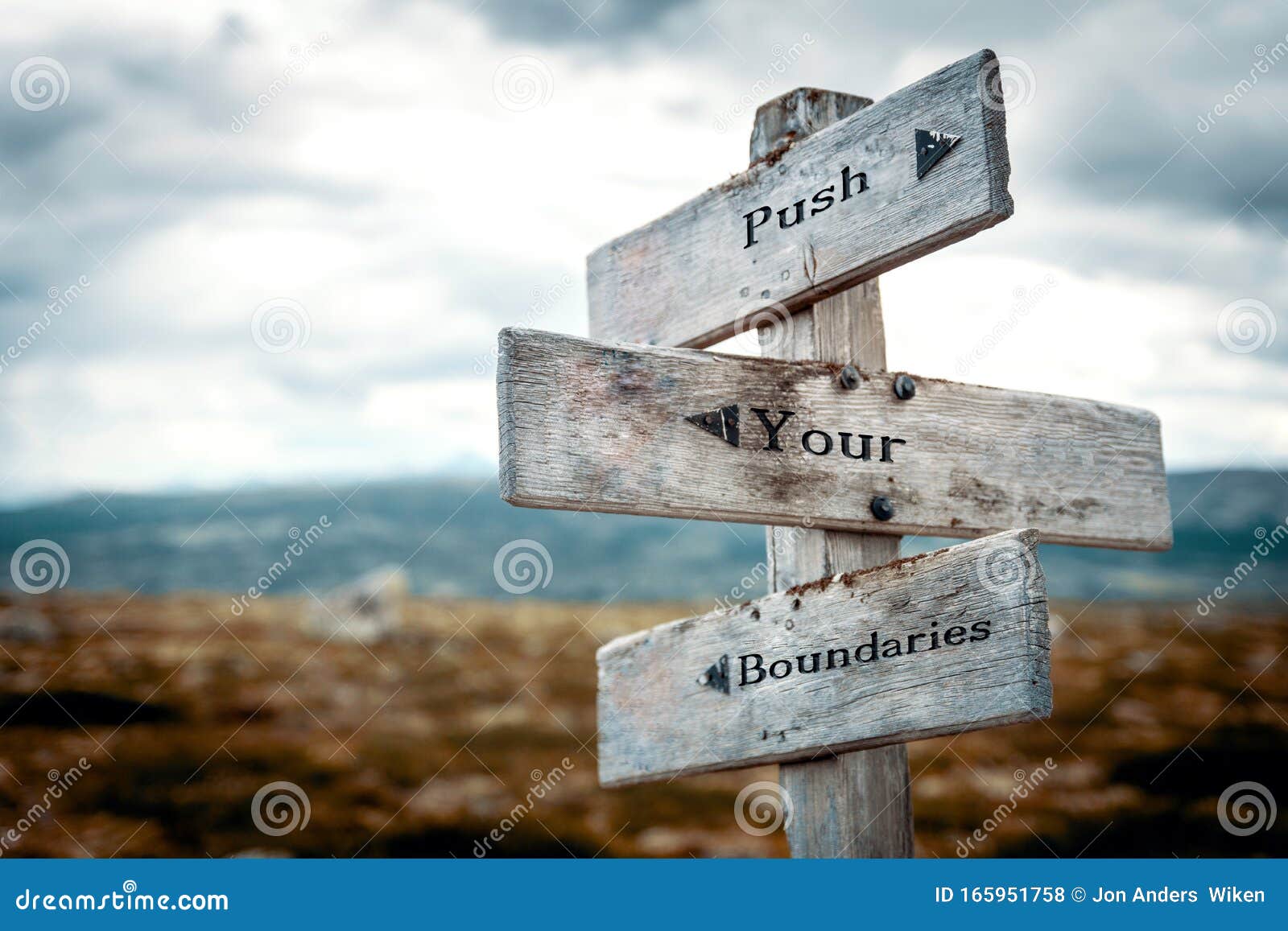 push your boundaries text on wooden rustic signpost outdoors in nature/mountain scenery.