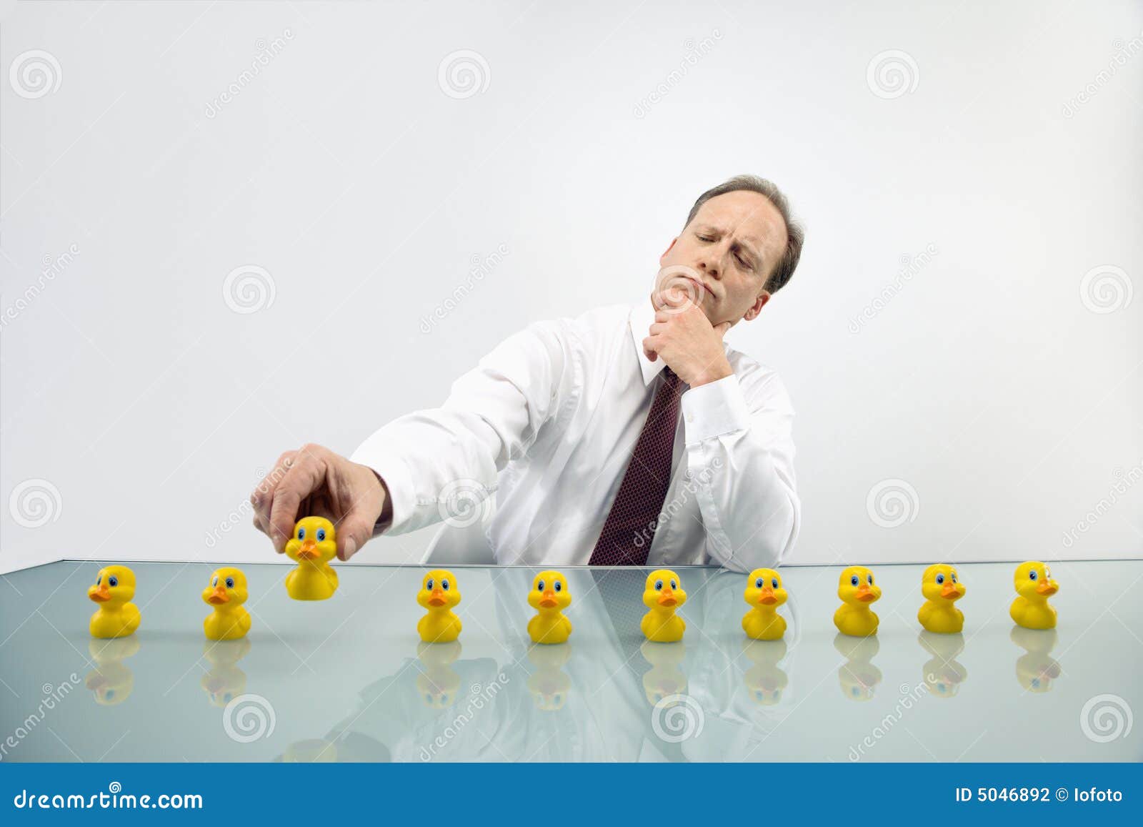 Putting business in order. Portrait of middle aged Caucasian businessman sitting at desk with ducks in a row.