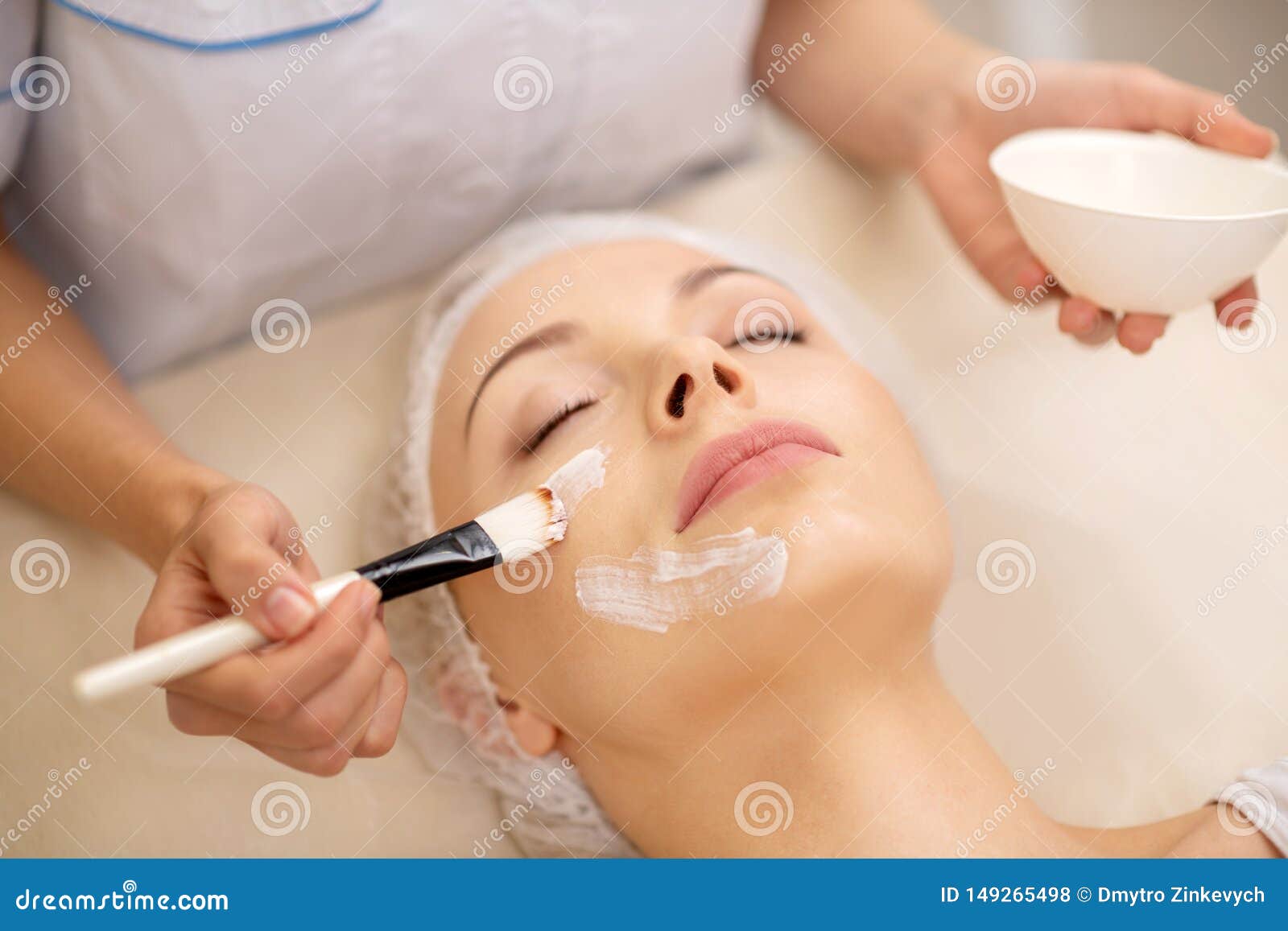 Dermatologist Using Cosmetics Brush while Putting Face Mask on Stock