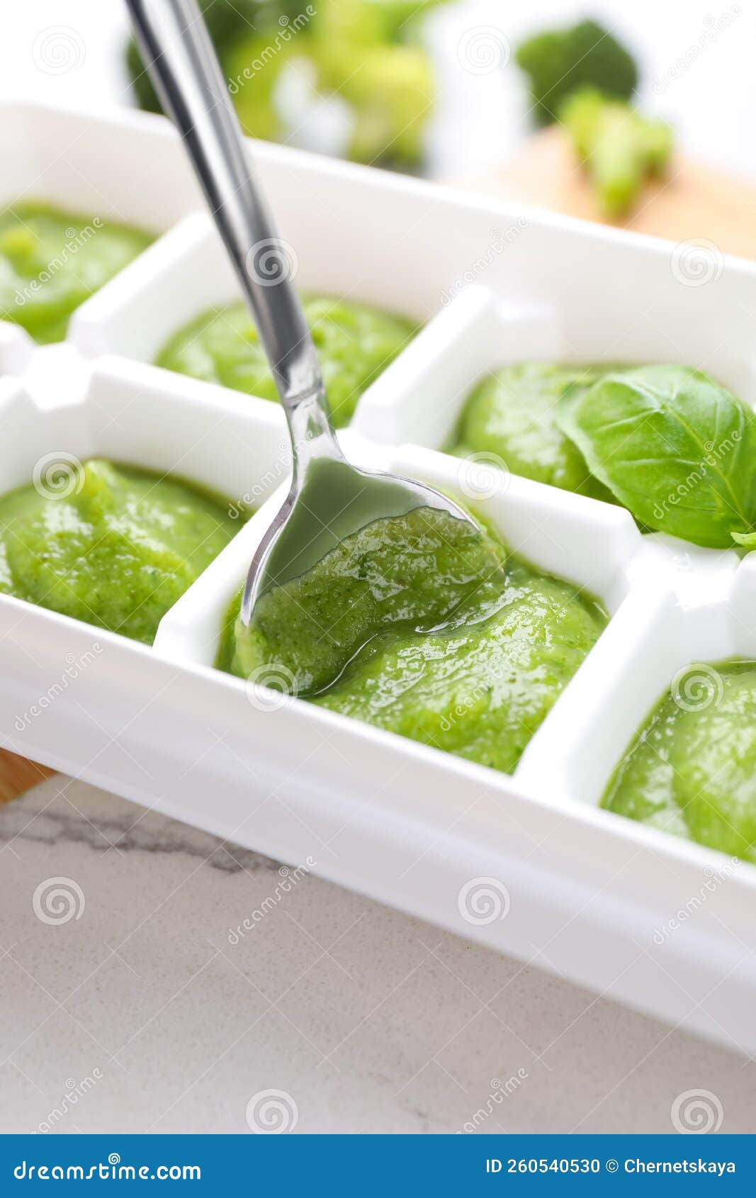 Putting Puree with Spoon into Ice Cube Tray on Table, Closeup. Ready