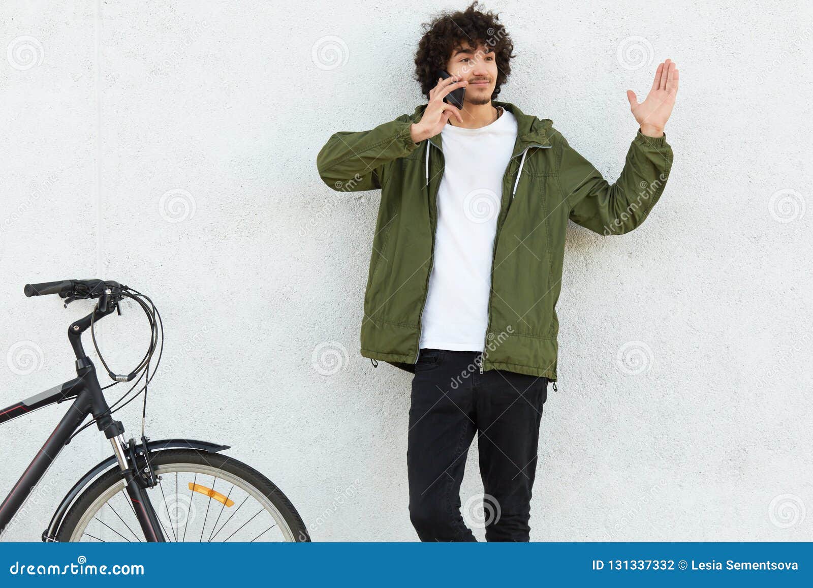 puzzled hesitant guy has telephone conversation, raises hand with bewilderment, cant make choice while recieves suggestion, poses