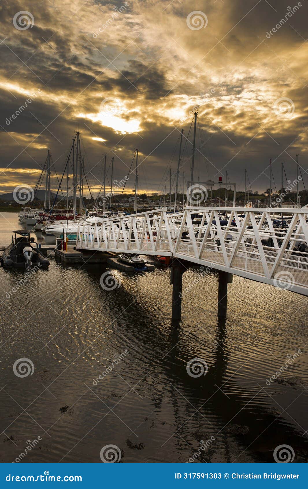 pwllheli marina, walkway gantry access to boats, in late evening sunlight.