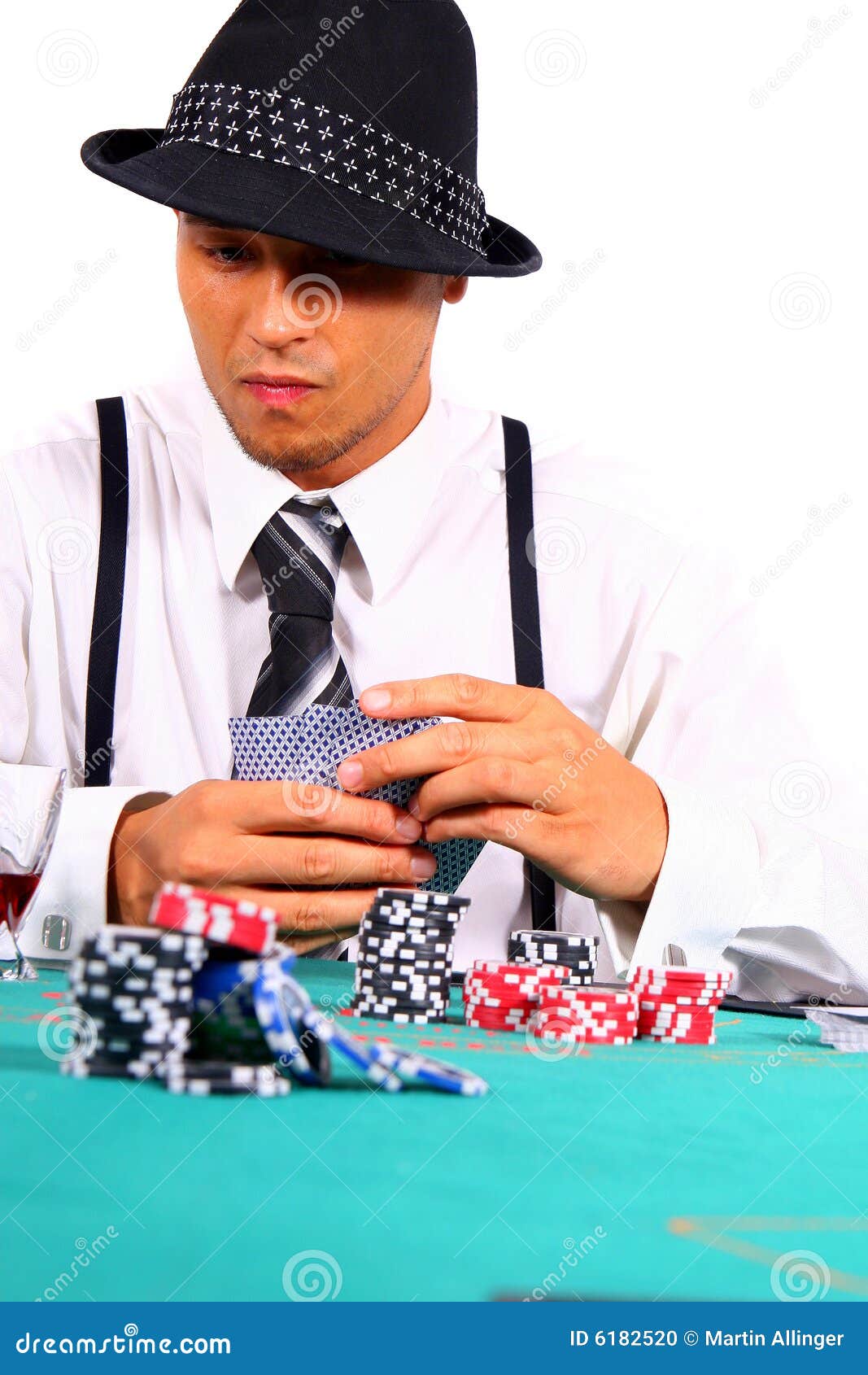 Póquer no estilo. Homem novo que joga o póquer com um chapéu e um terno à moda. Isolado sobre o fundo branco.