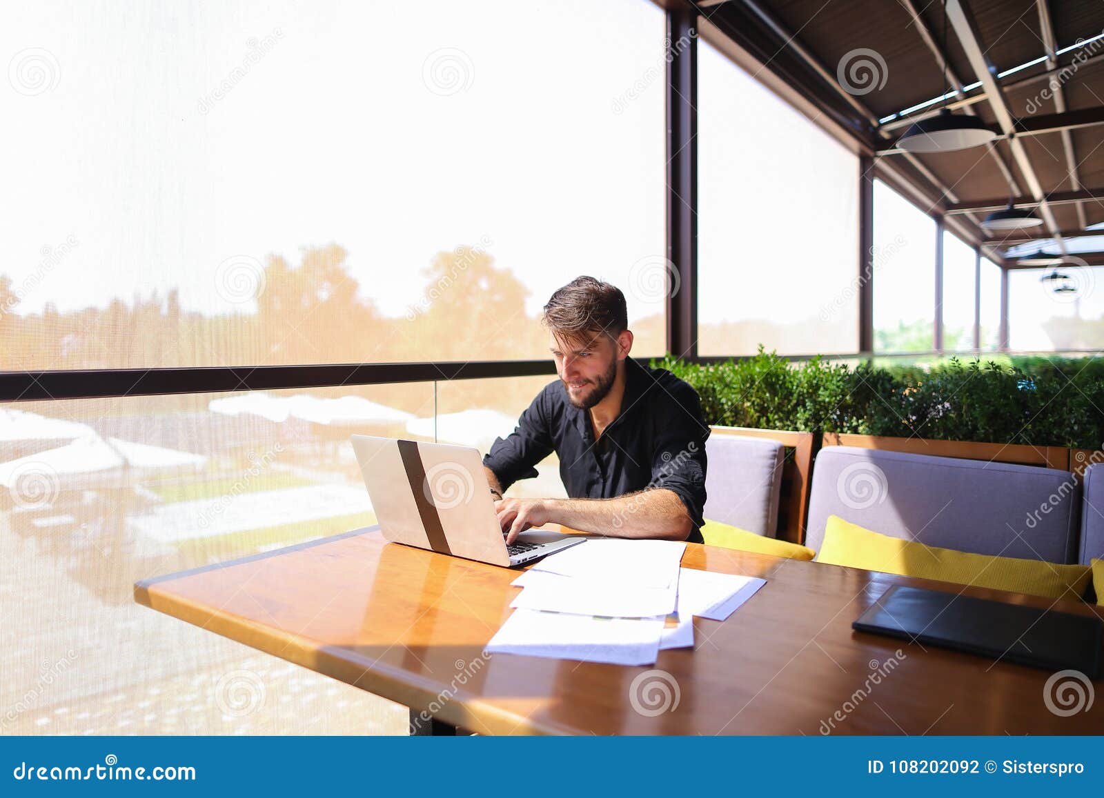 Quantity Surveyor Working At Cafe Table With Papers And Laptop