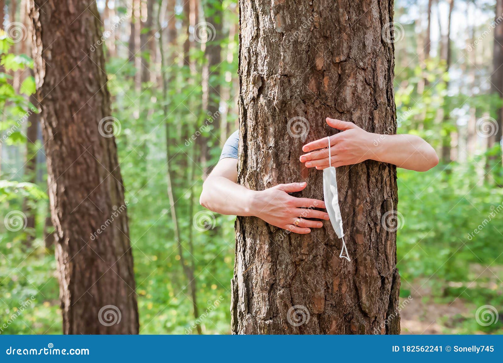 quarantine end concept. hands hug a tree close-up and copy space. hands hold, throw out a medical mask