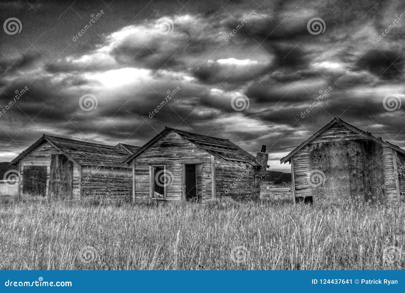 Quelques quarts vivants rustiques abandonnés en noir et blanc avec un ciel dramatique à l'arrière-plan et un champ herbeux dans le premier plan près de l'anaconda et du Fairmont jaillit station de vacances au Montana