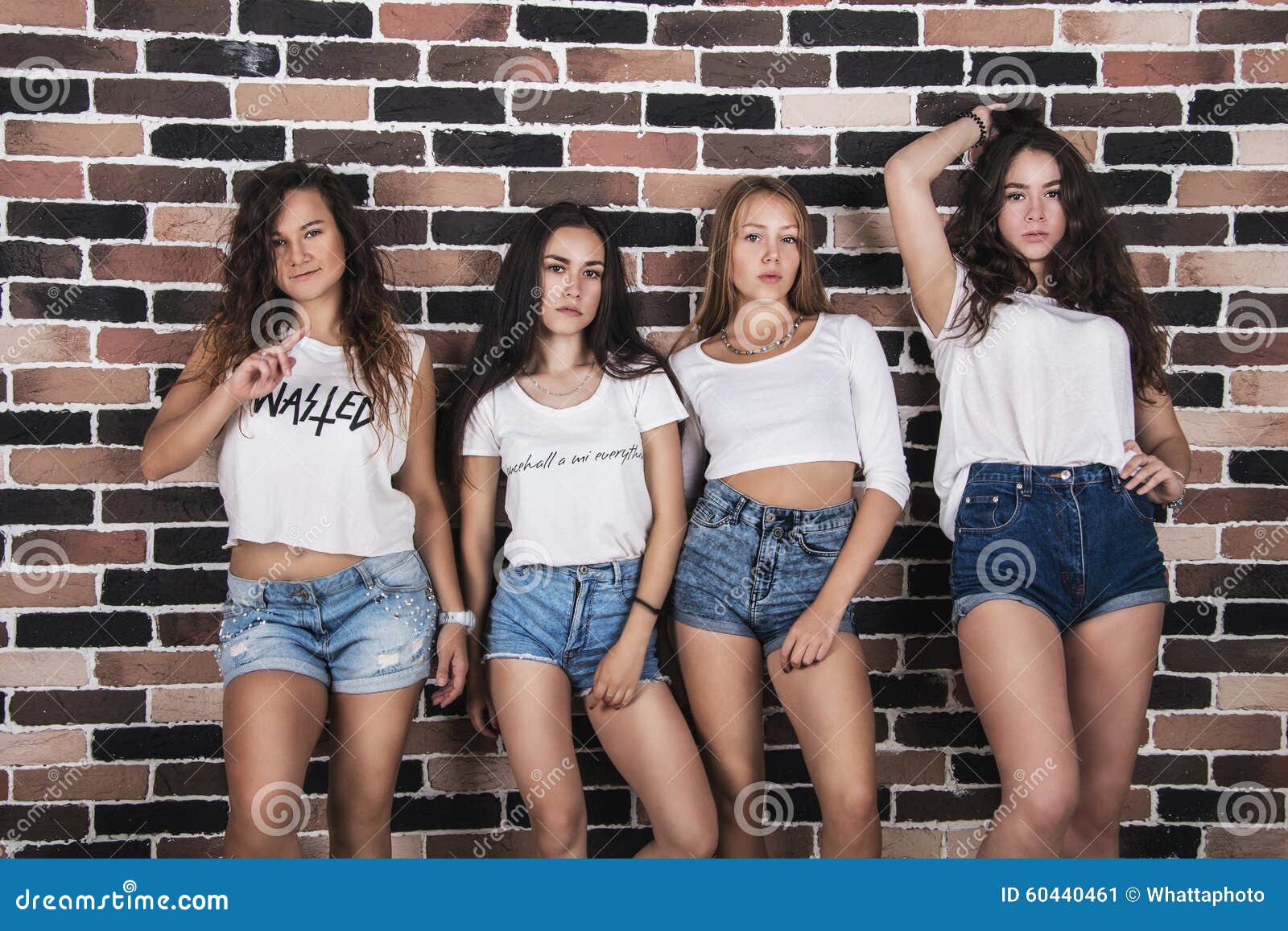 Quatre Jeunes Filles Dans Les Shorts Blancs De T Shirts Et De Jeans Tenant Le Nea Image Stock