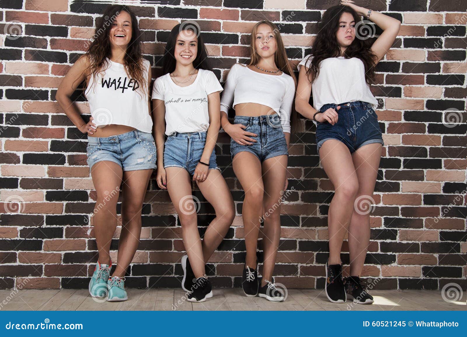 Quatre Jeunes Filles Dans Les Shorts Blancs De T Shirts Et De Jeans Tenant Le Nea Image Stock