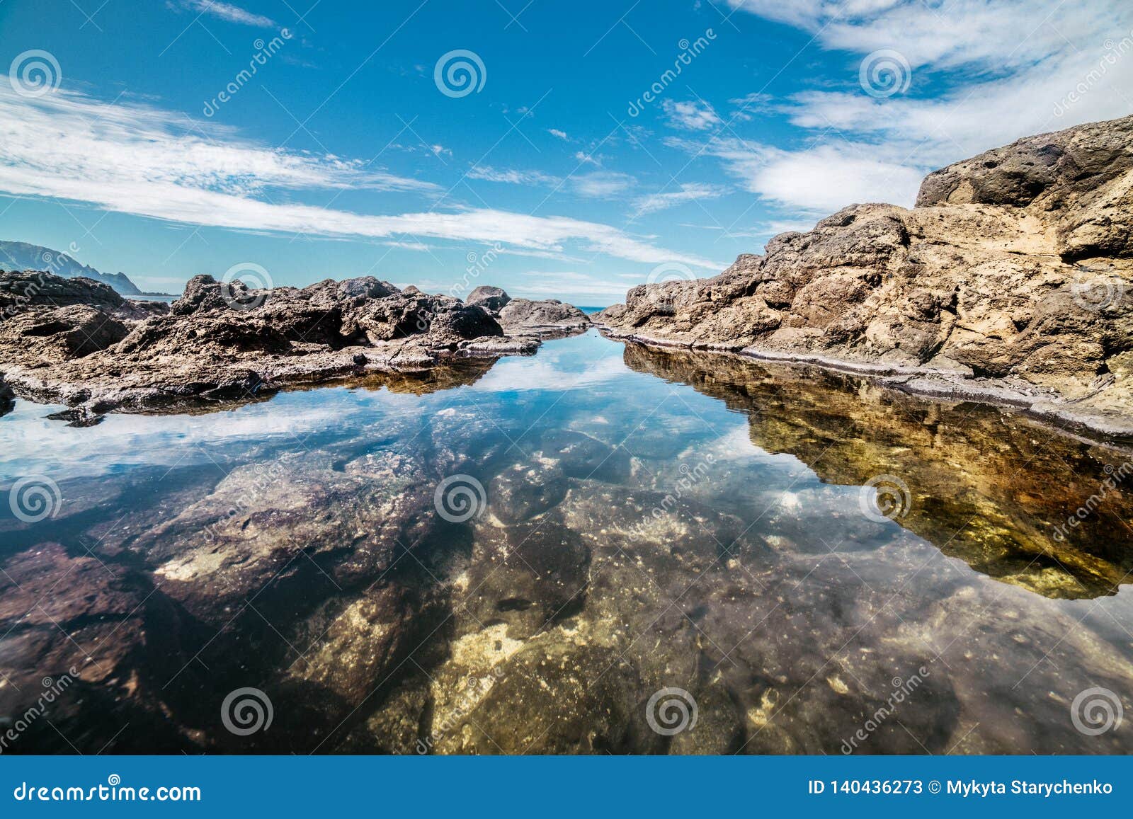 queen`s bath on kauai, hawaii island. ocean pond in rocks with sky reflection