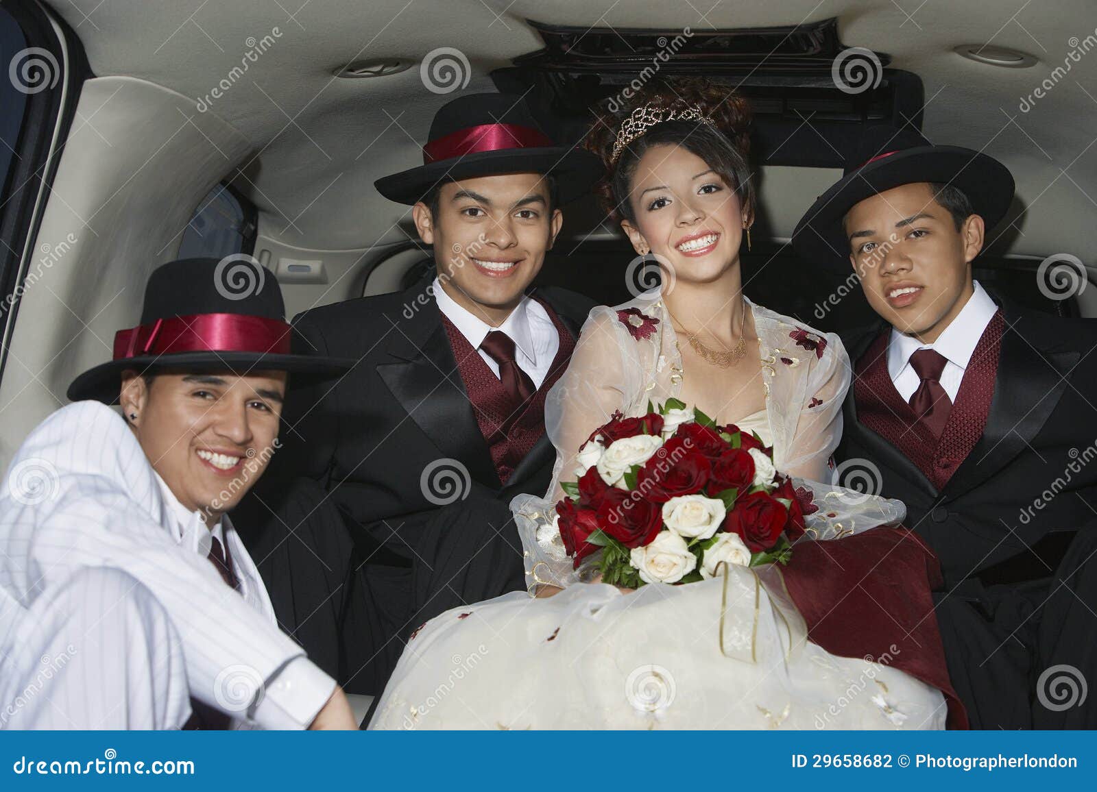 Porträt von einem schönen Quinceanera, das mit drei männlichen Freunden in der Limousine sitzt