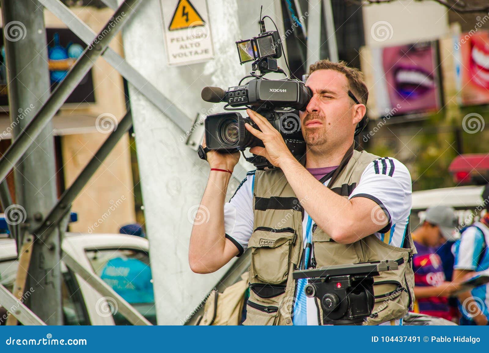 QUITO, ECUADOR - OCTOBER 11, 2017: Close up of camarographer recovering all the interview with the fans of Ecuador and Argentina, with a crowd of people screaming and jumping supporting their team.