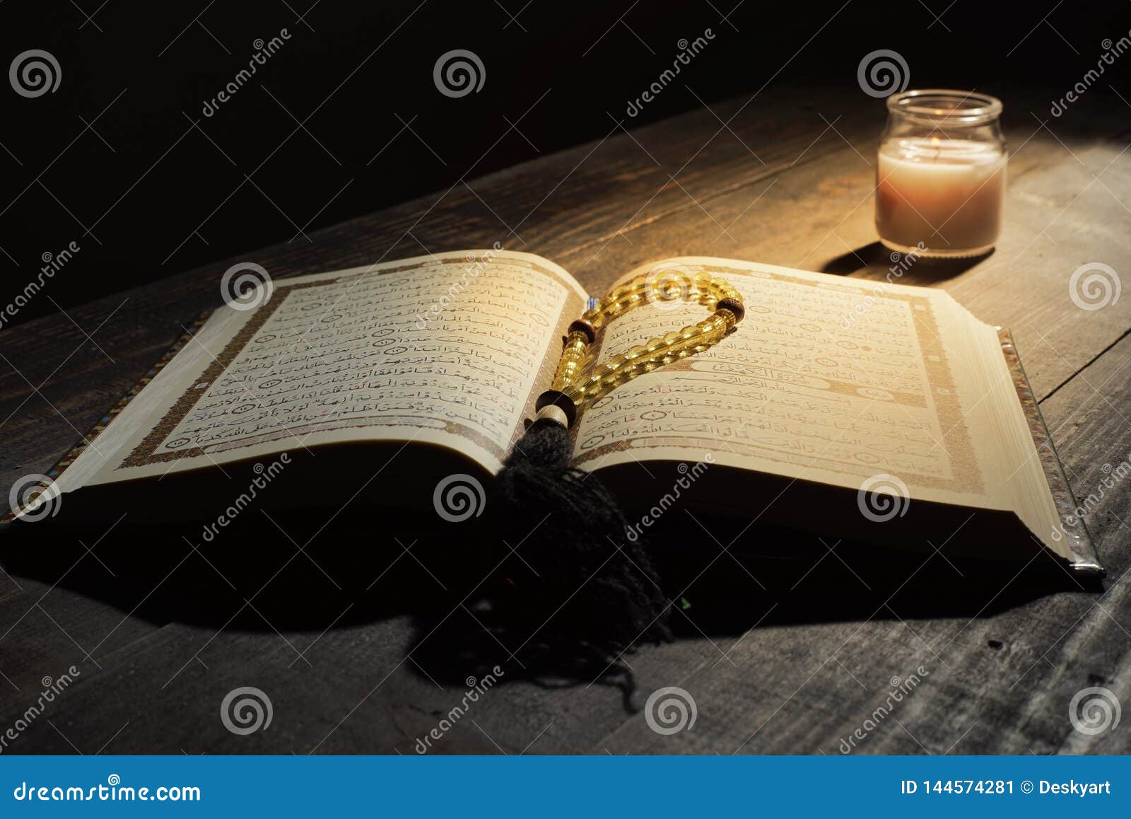 the qur`an, the holy book of islam. worship month of ramadan, reading the scriptures by using a candle light.