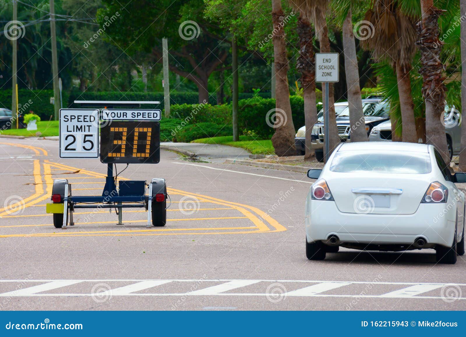 radar speed limit indicator sign showing 30 proving a passing car is speeding as it drives down the road in a school zone