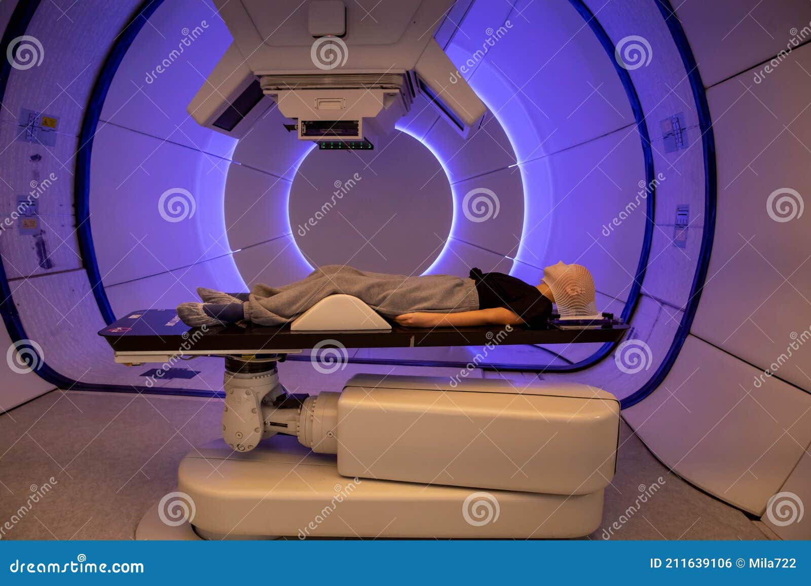 radiation proton therapy. brain cancer child patient lying on positioning bed with fixing mask on her head