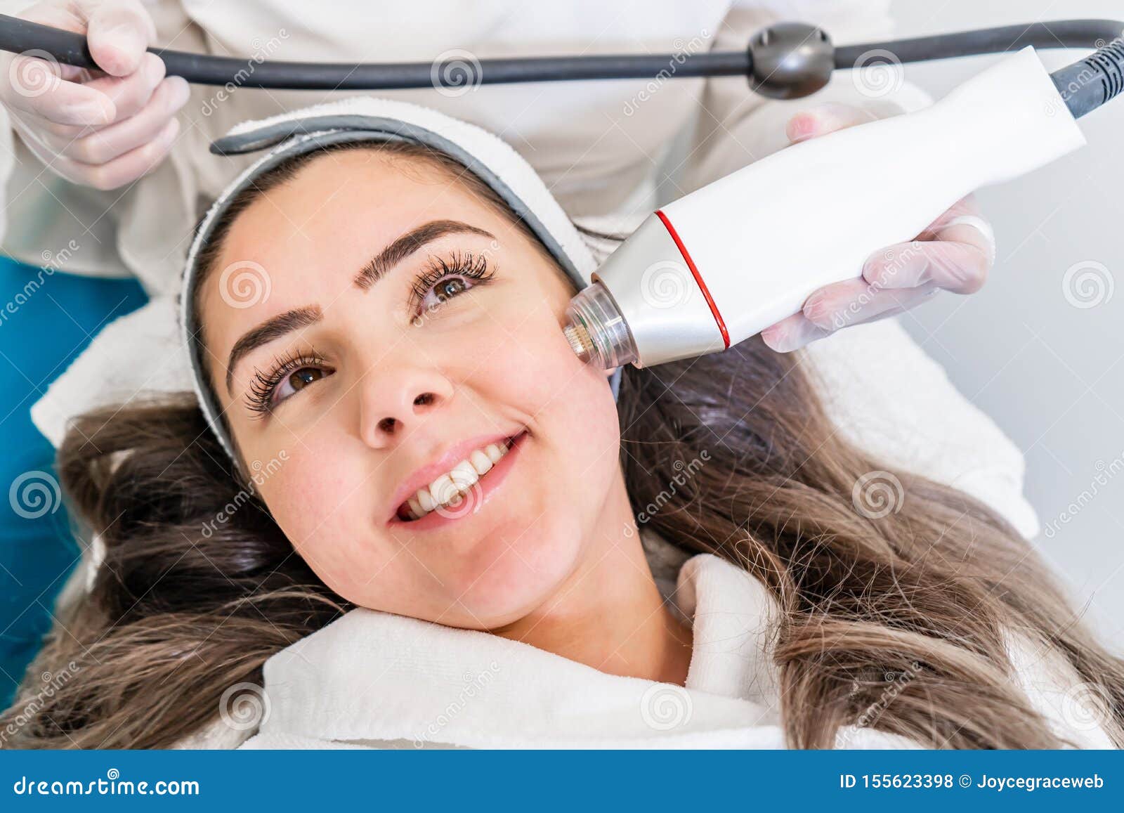 radio frequency microneedling machine handpiece on the cheek of a woman`s face during a beauty skin tightening treatment