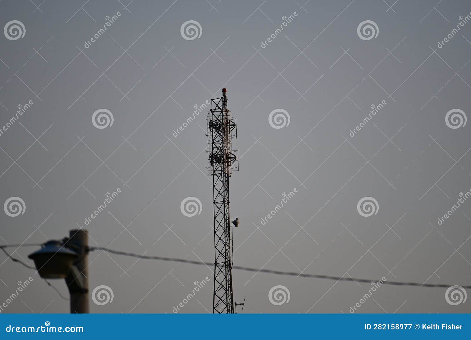 Radio Tower with Power Lines and Light Pole in Front of it Stock Image