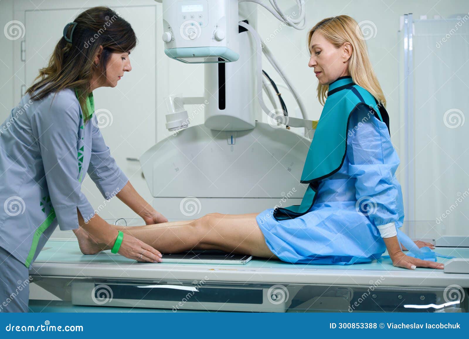 qualified radiographic technologist preparing woman for x-ray of knee joints